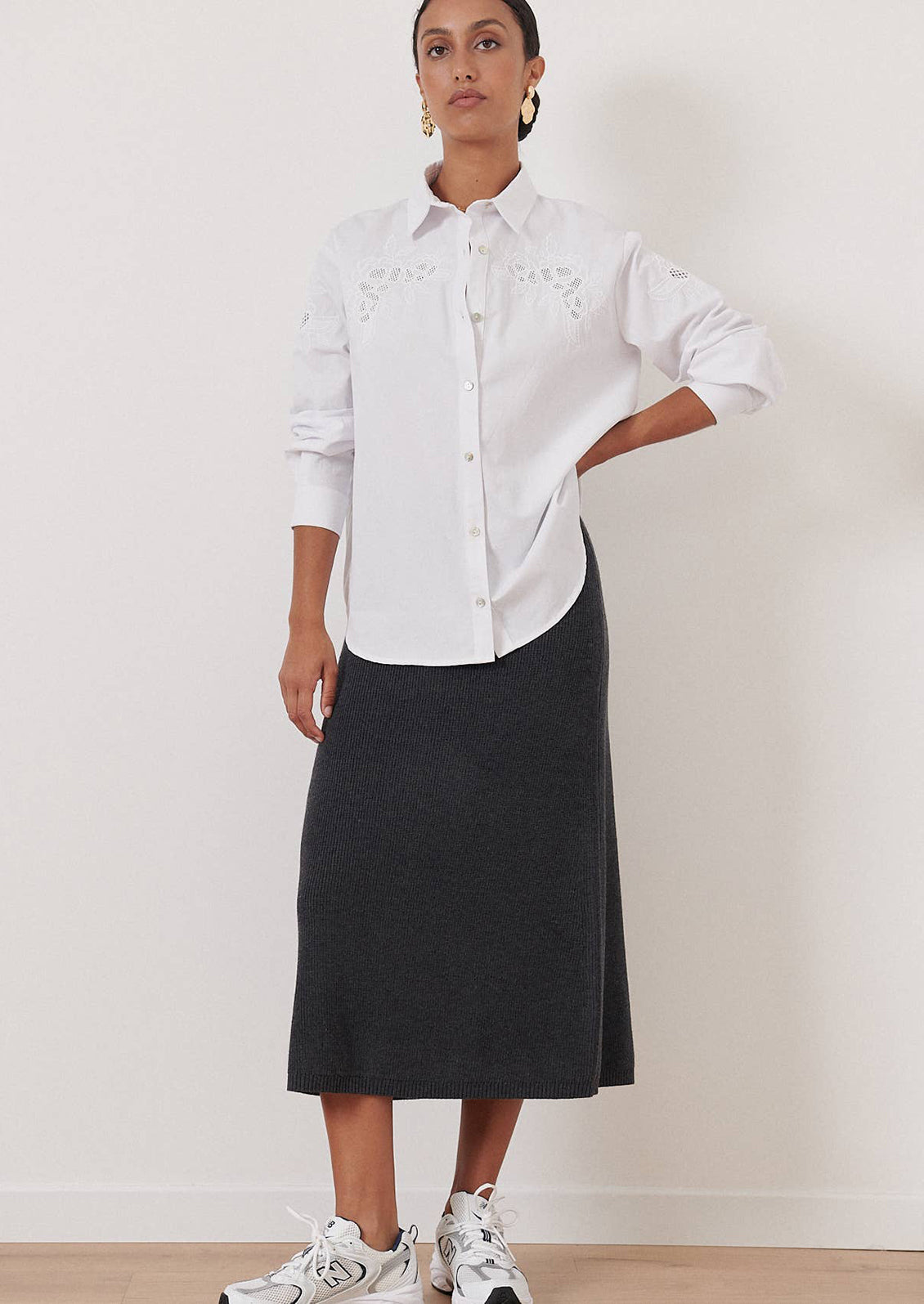 A woman wearing a white button down shirt with eyelet embroidery at yoke.