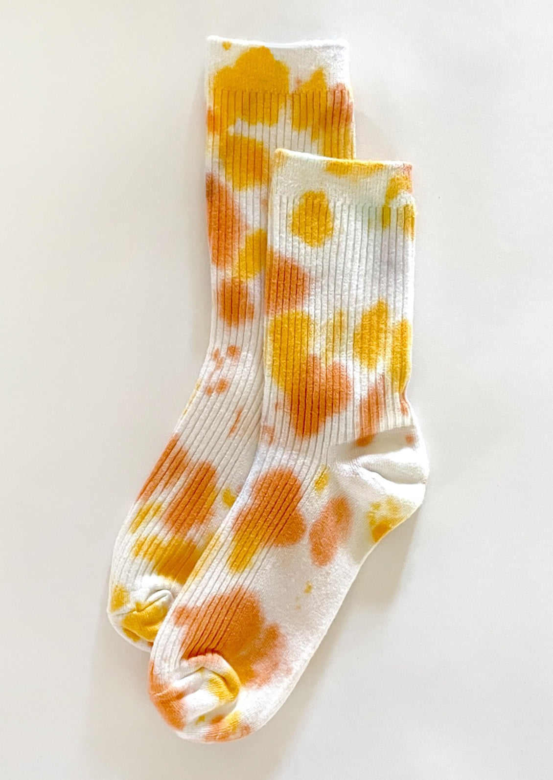 A pair of tie dye socks in yellow and orange color.