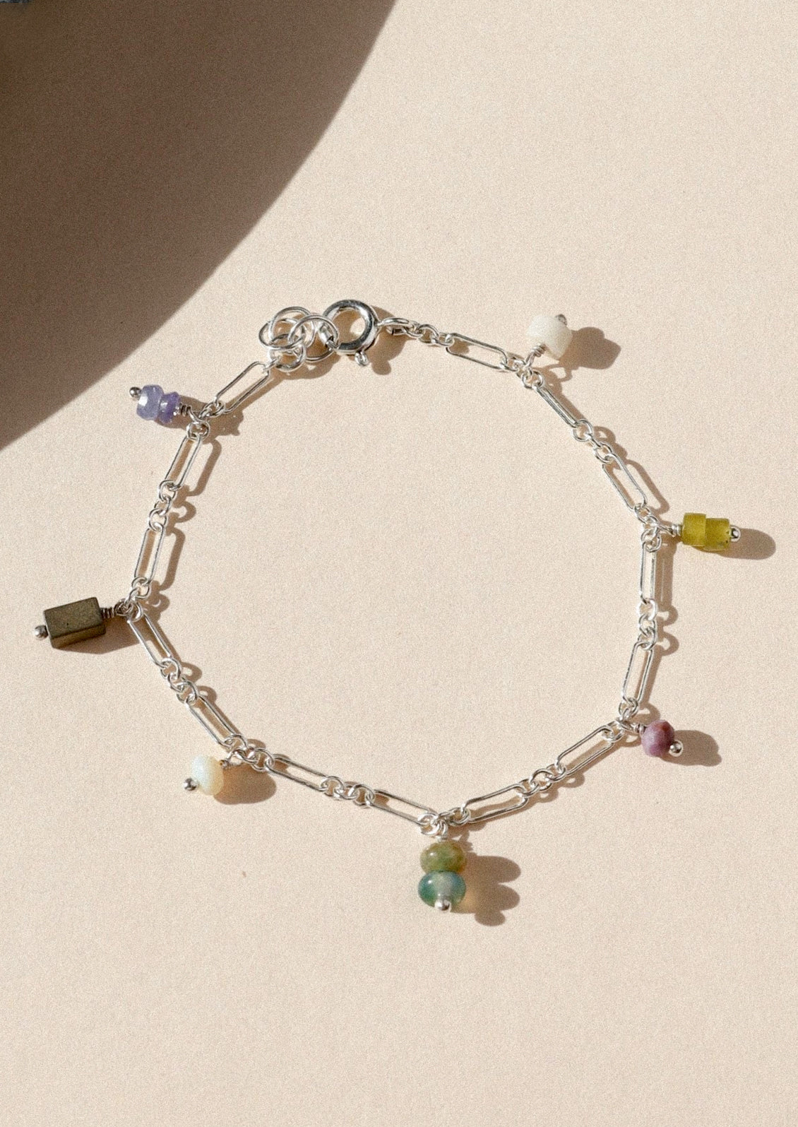 A sterling silver chain bracelet with various colored gems.