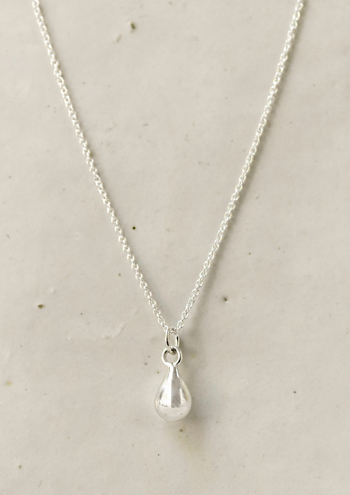 A sterling silver necklace with a dew drop shaped charm.