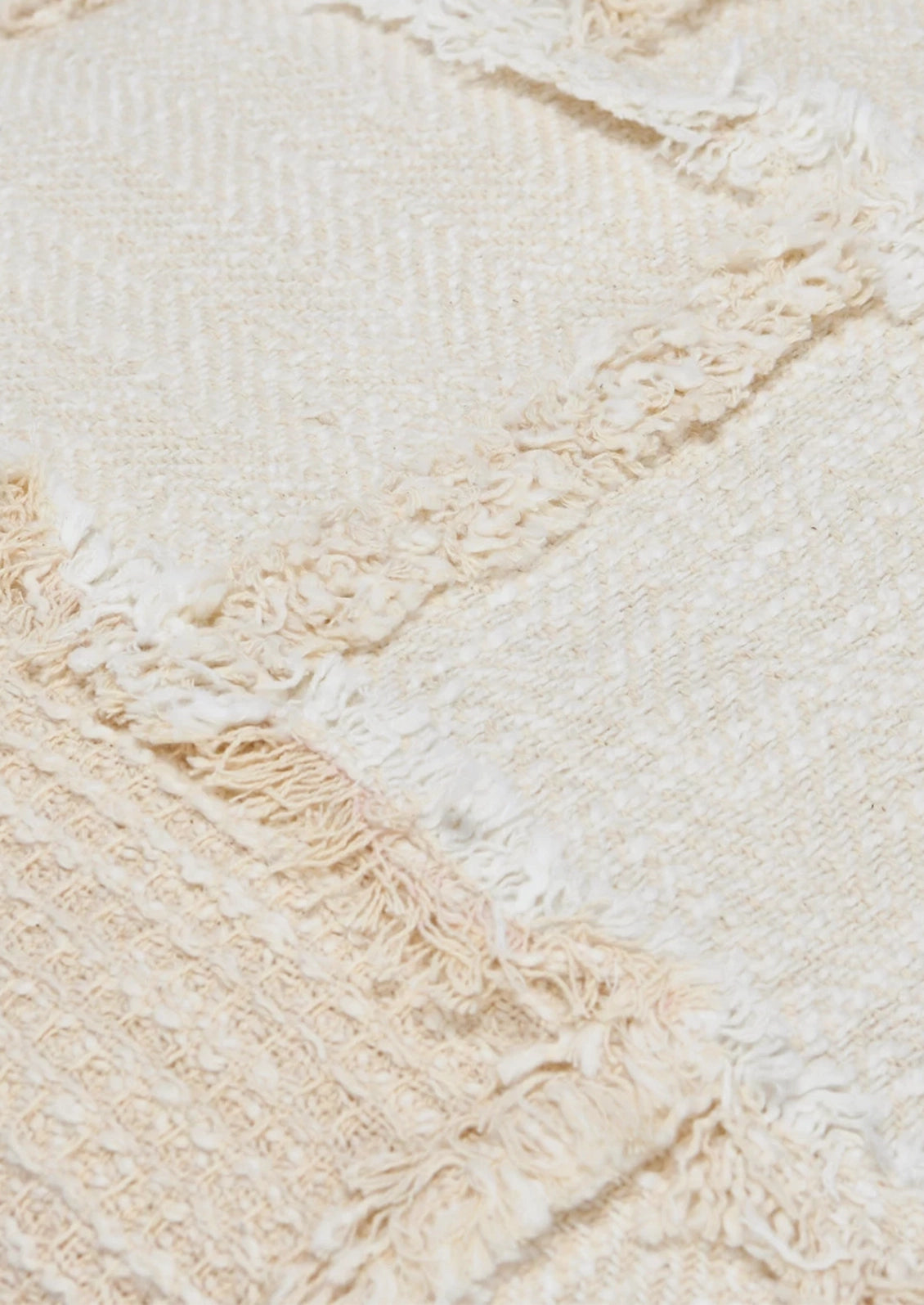 A throw pillow in natural cotton with patchwork detailing in different textures.
