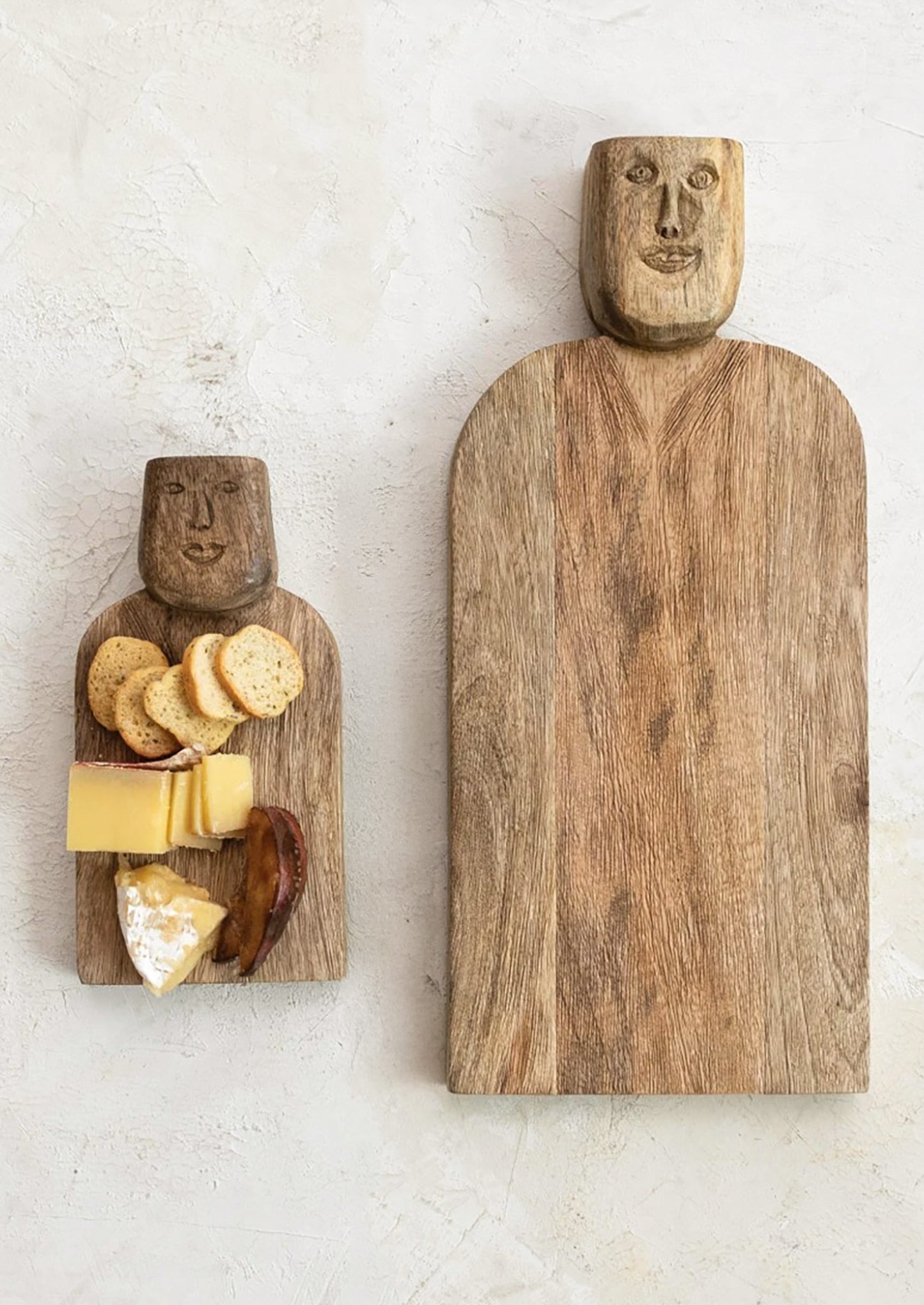 A small wooden serving board with a face carved into the handle.