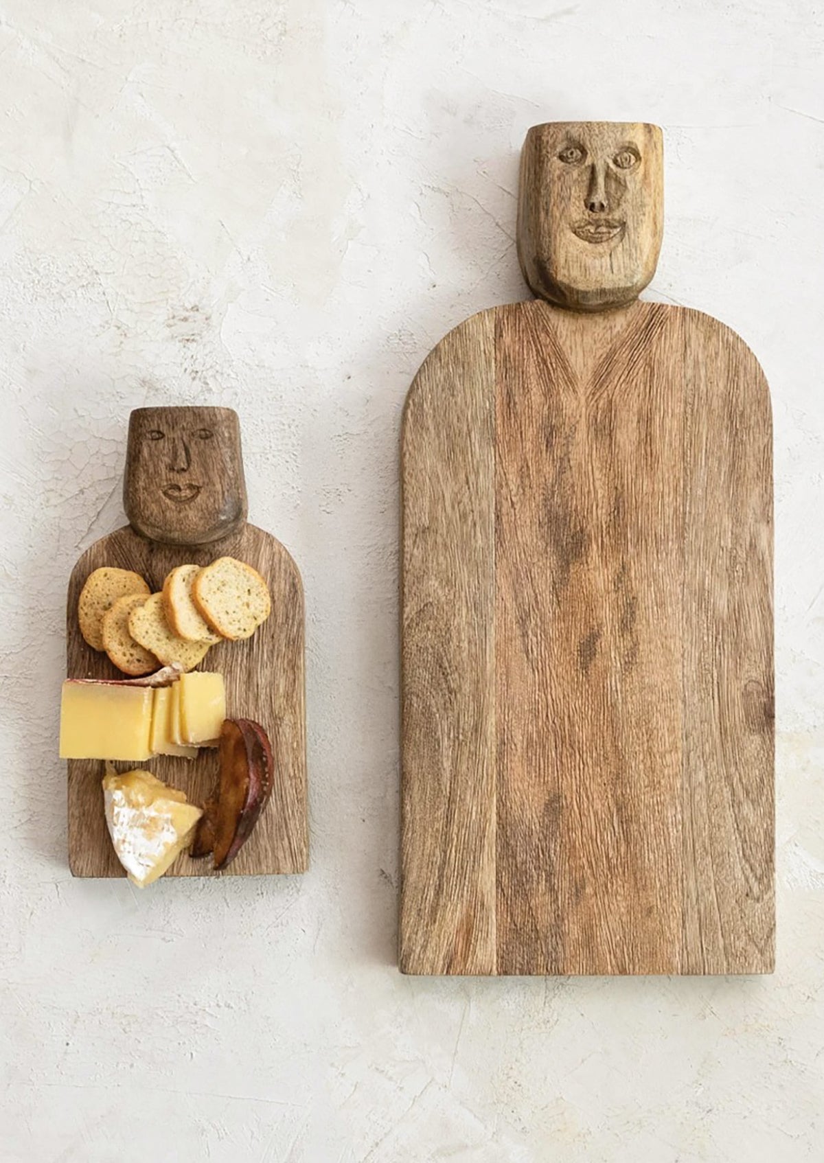 A small wooden serving board with a face carved into the handle.