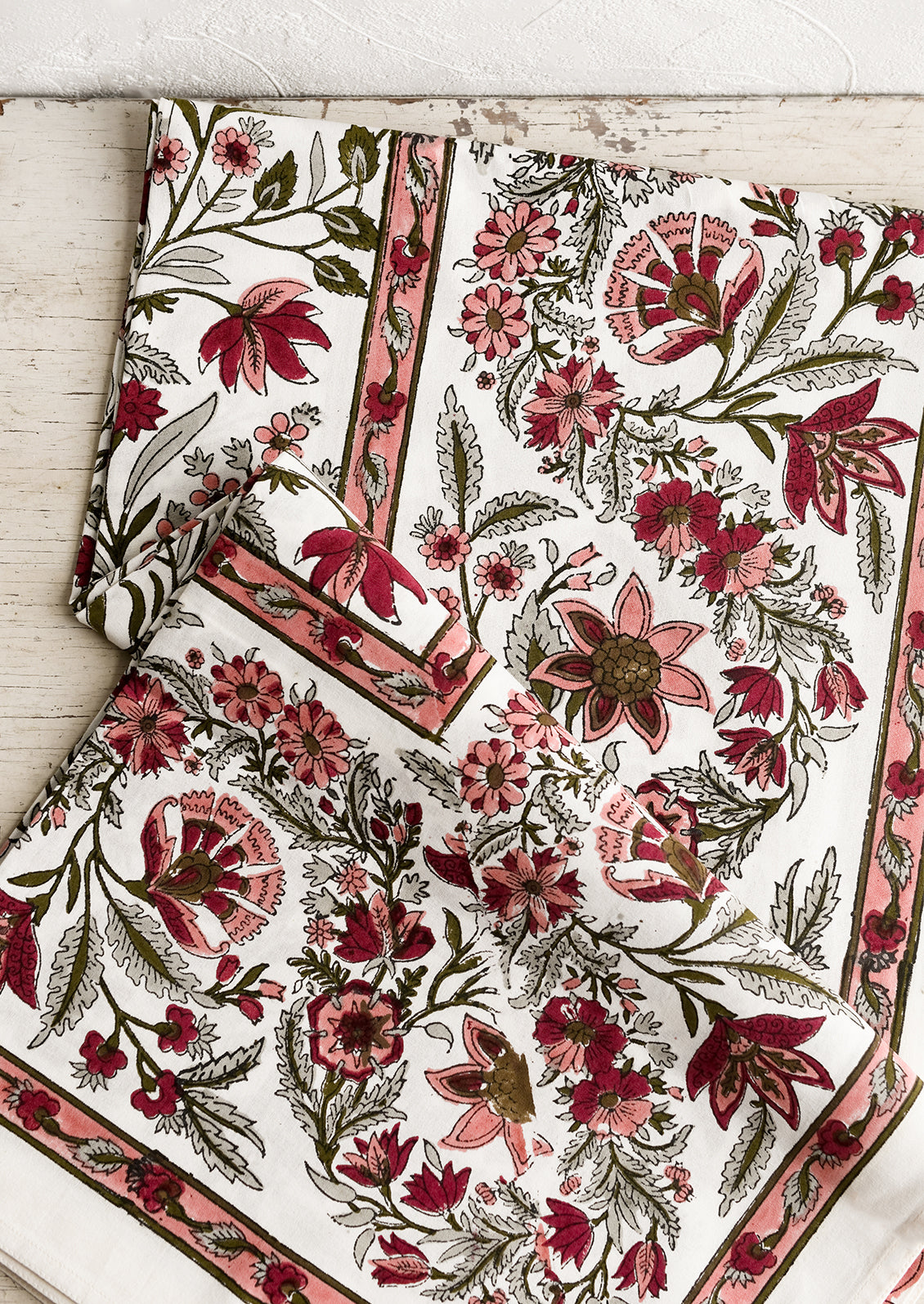 A block printed, floral patterned tablecloth in shades of pink and sage green.