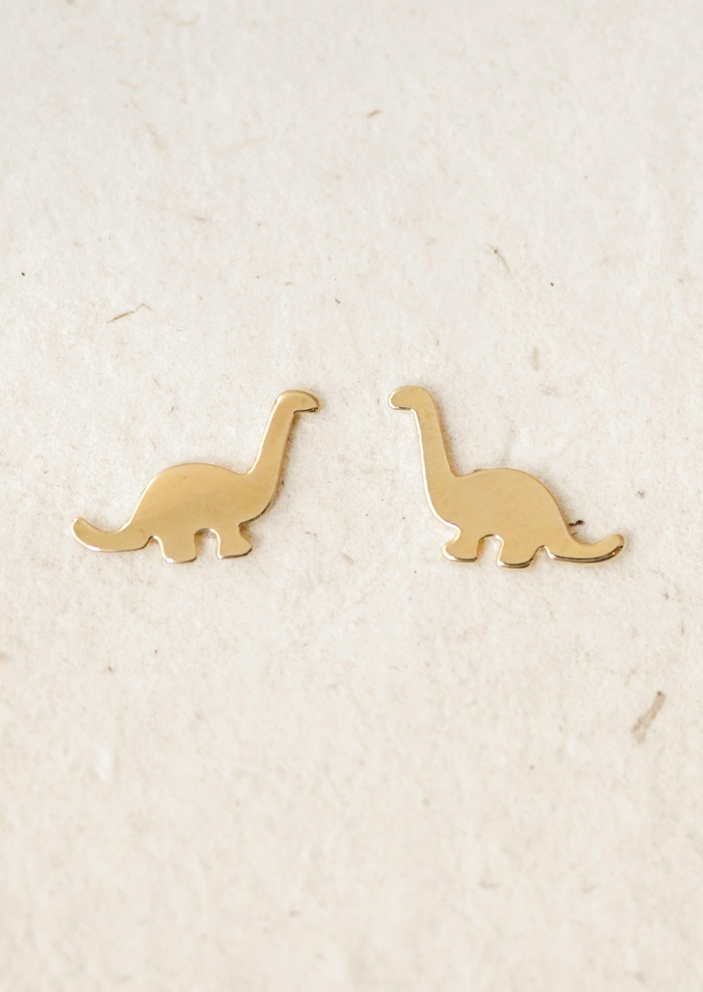 A pair of gold dinosaur stud earrings.