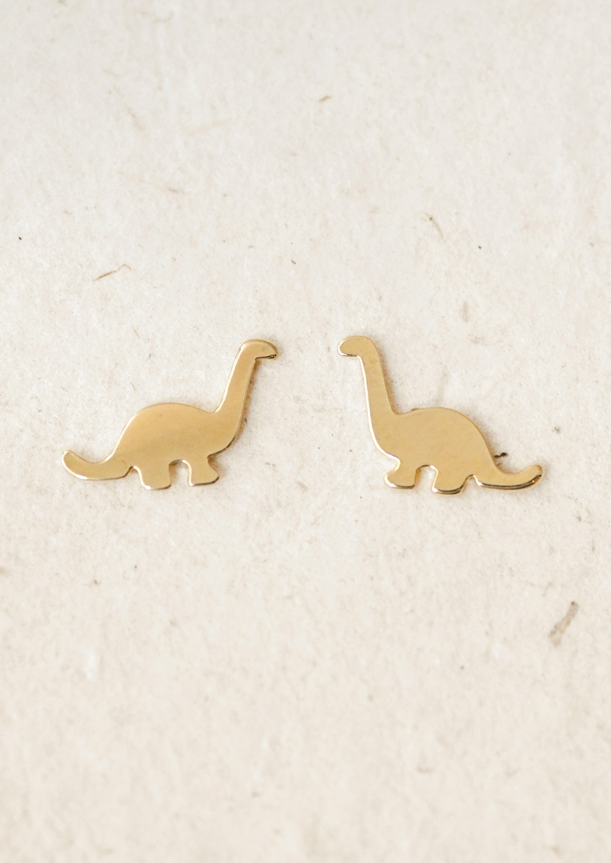 A pair of gold dinosaur stud earrings.