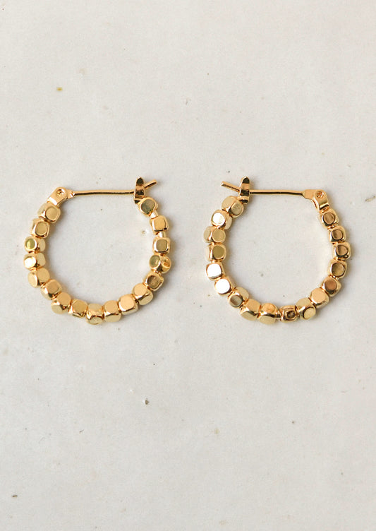 A pair of shiny gold hoop earrings made of gold beads.
