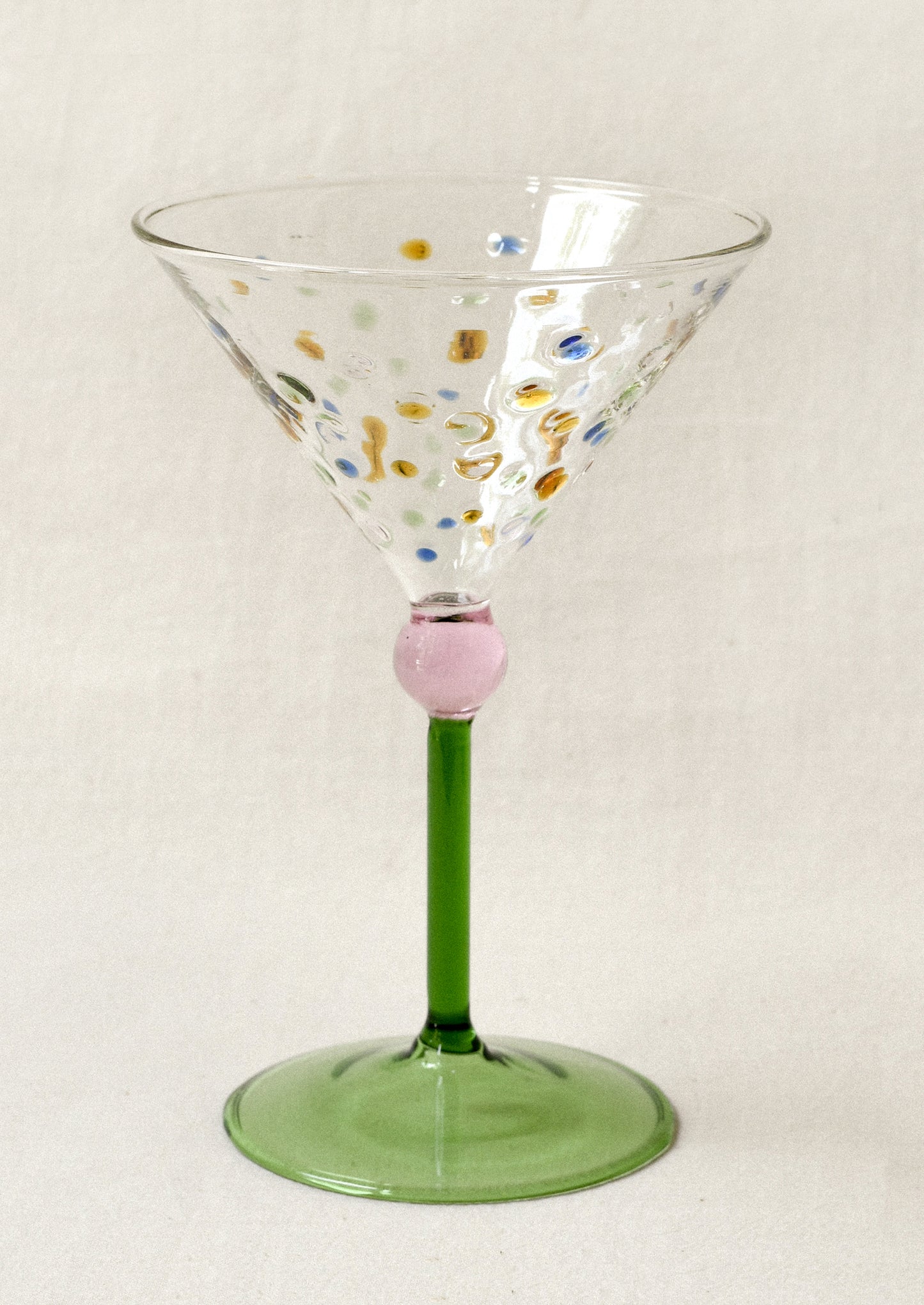 Decorative martini glass with colorful dots and green stem.