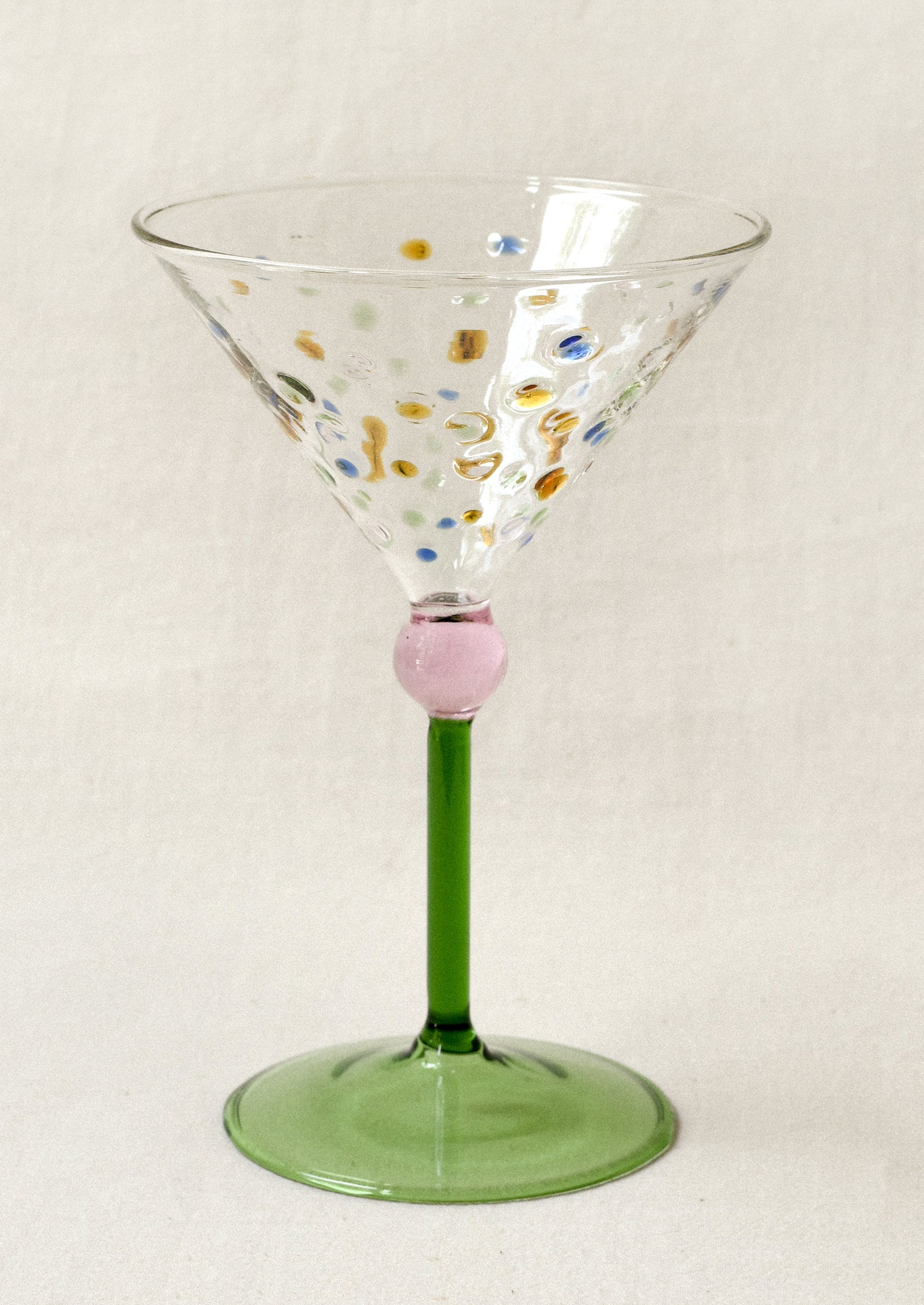 Decorative martini glass with colorful dots and green stem.