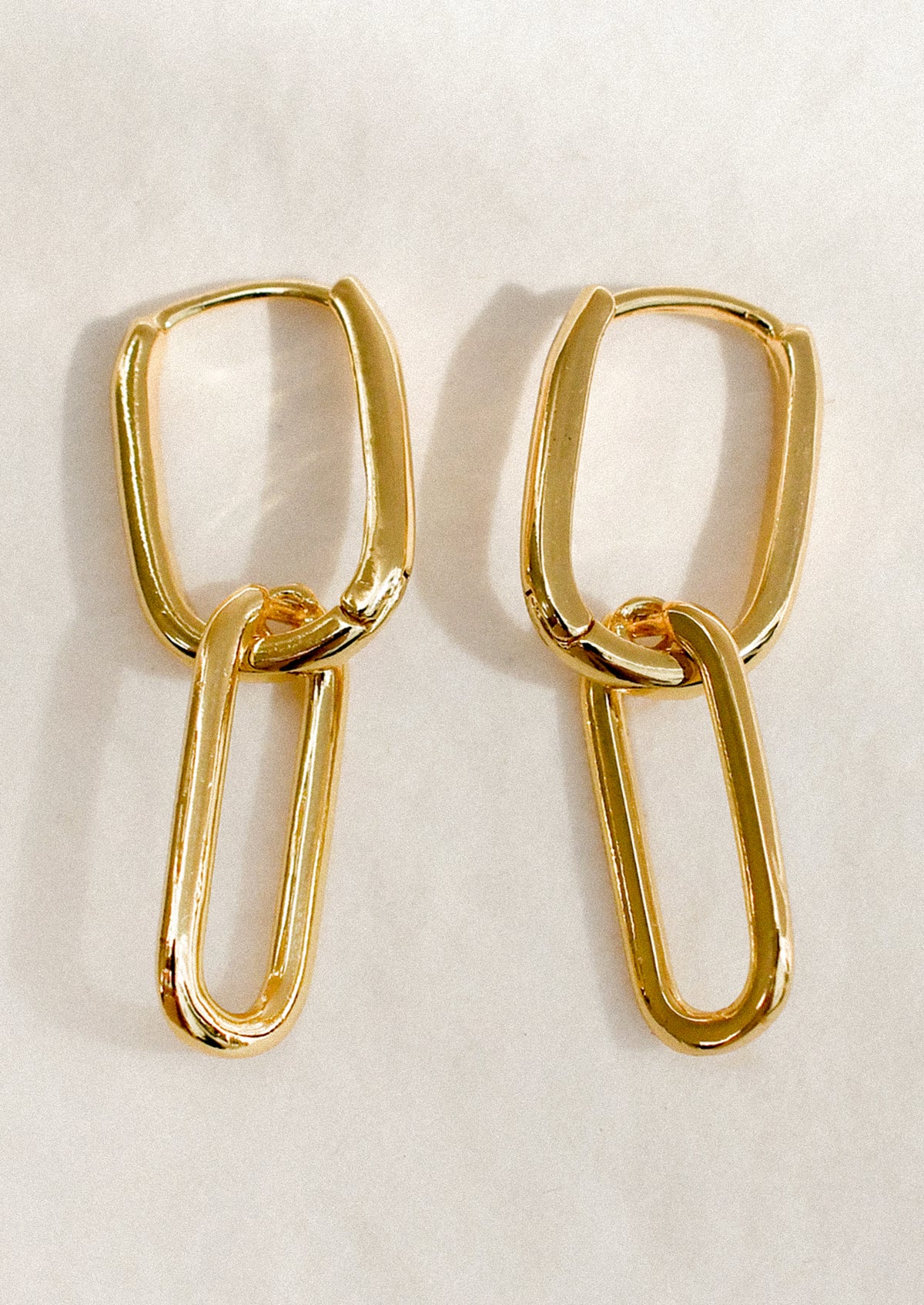 A pair of gold earrings with two oval links connected.