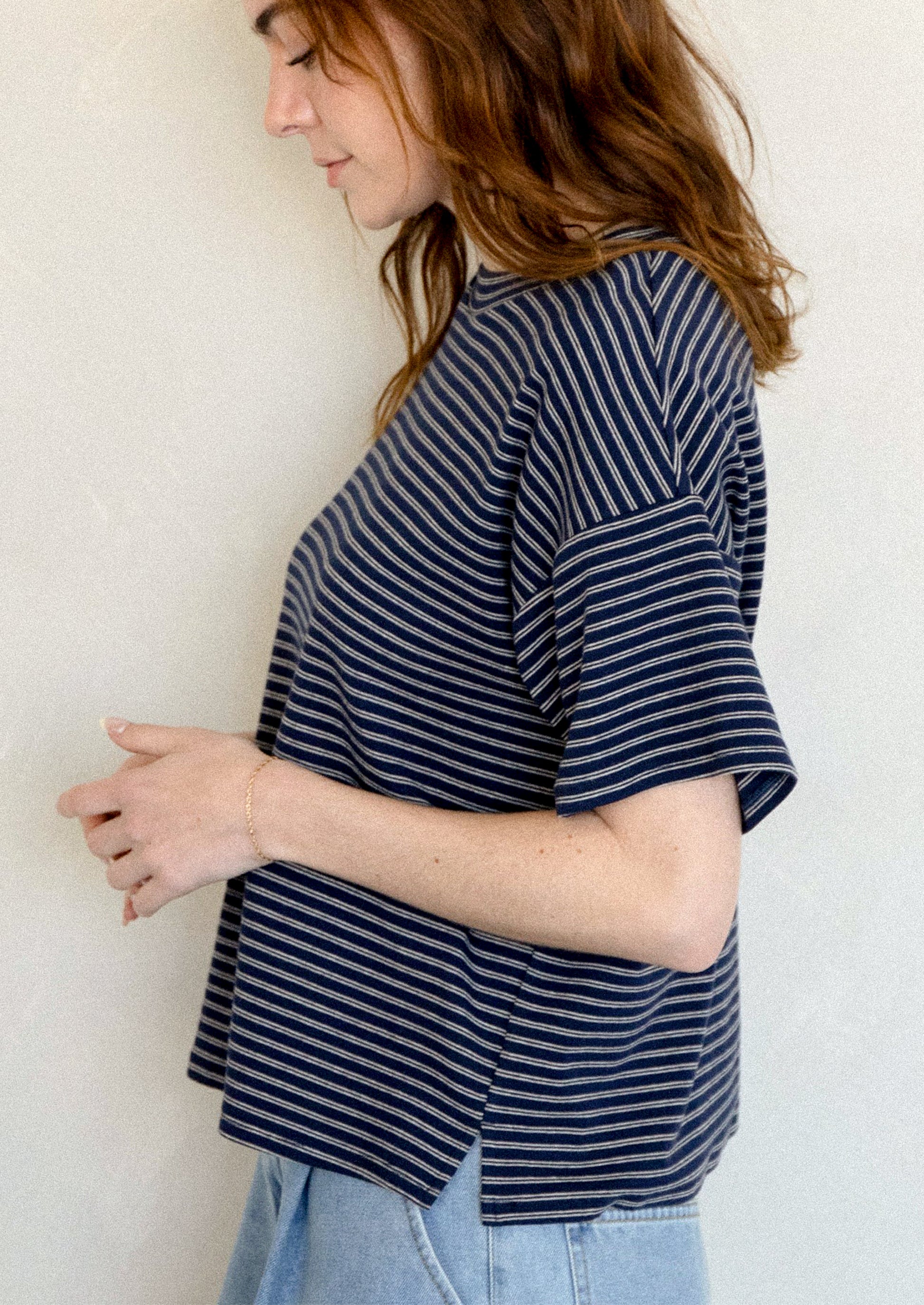 A woman wearing a slouchy t-shirt in navy with thin white stripes.