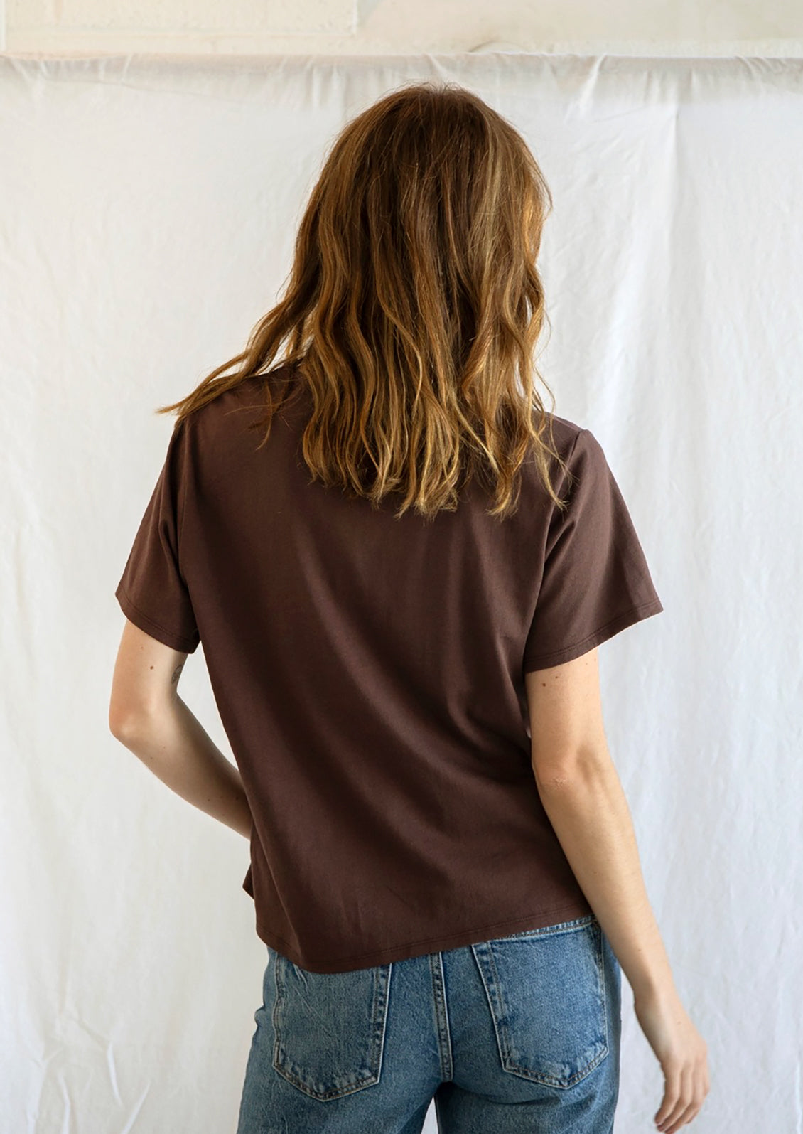 A woman wearing a short sleeve cotton t-shirt in chocolate brown.