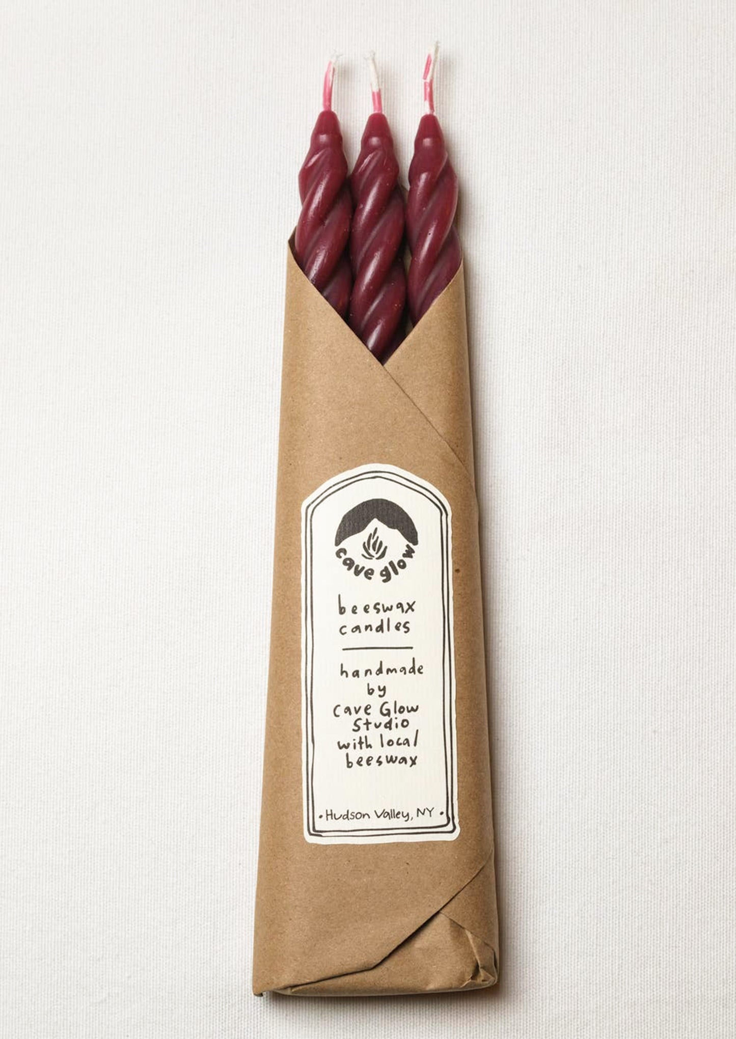A set of three spiral textured taper candles in dark red color.