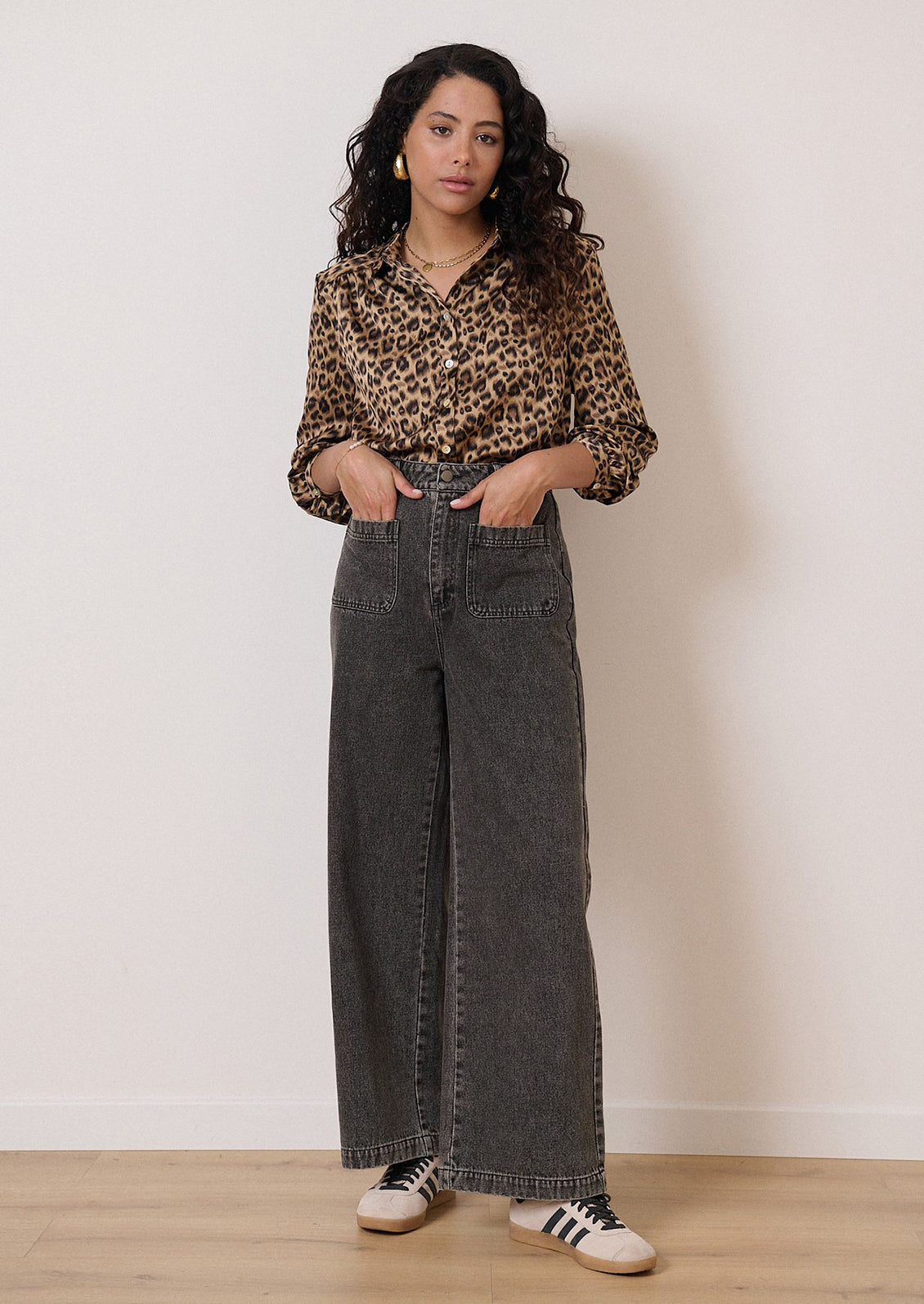 A woman wearing a long sleeve leopard print collared shirt.