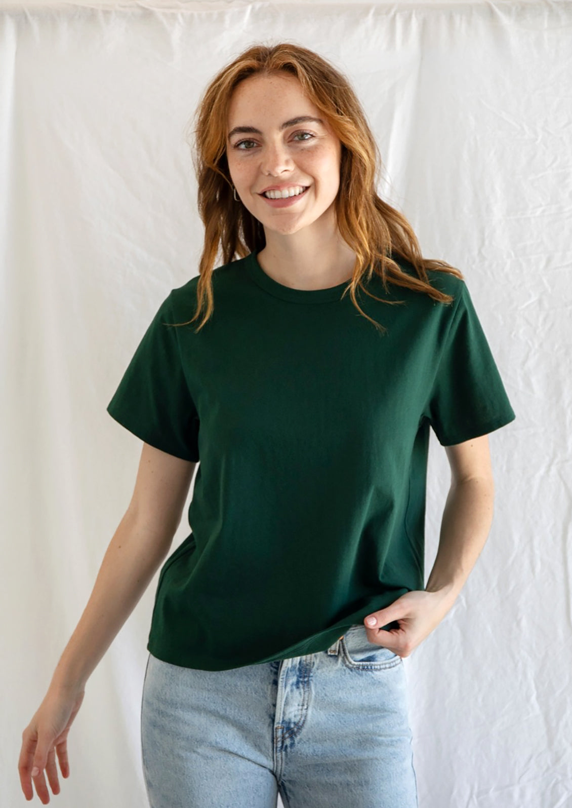 A woman wearing a short sleeve cotton t-shirt in emerald green.