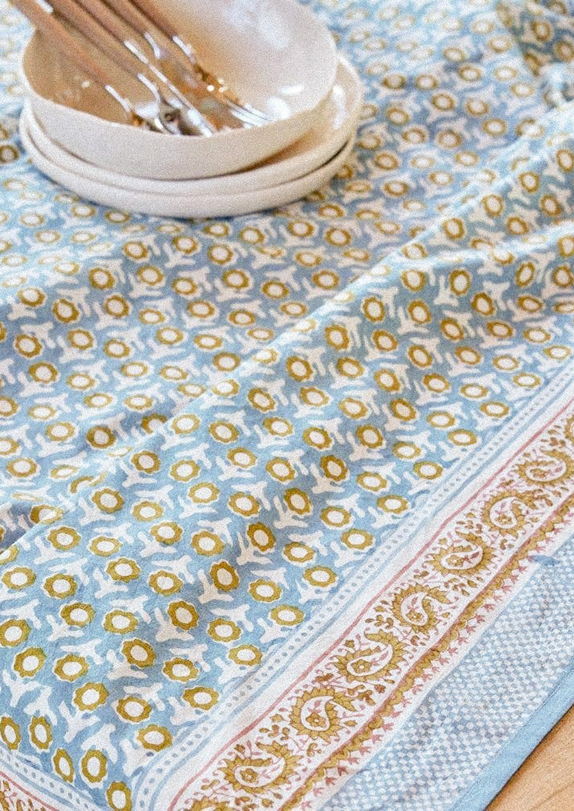 A block printed tablecloth in light blue and mustard paisley floral print.