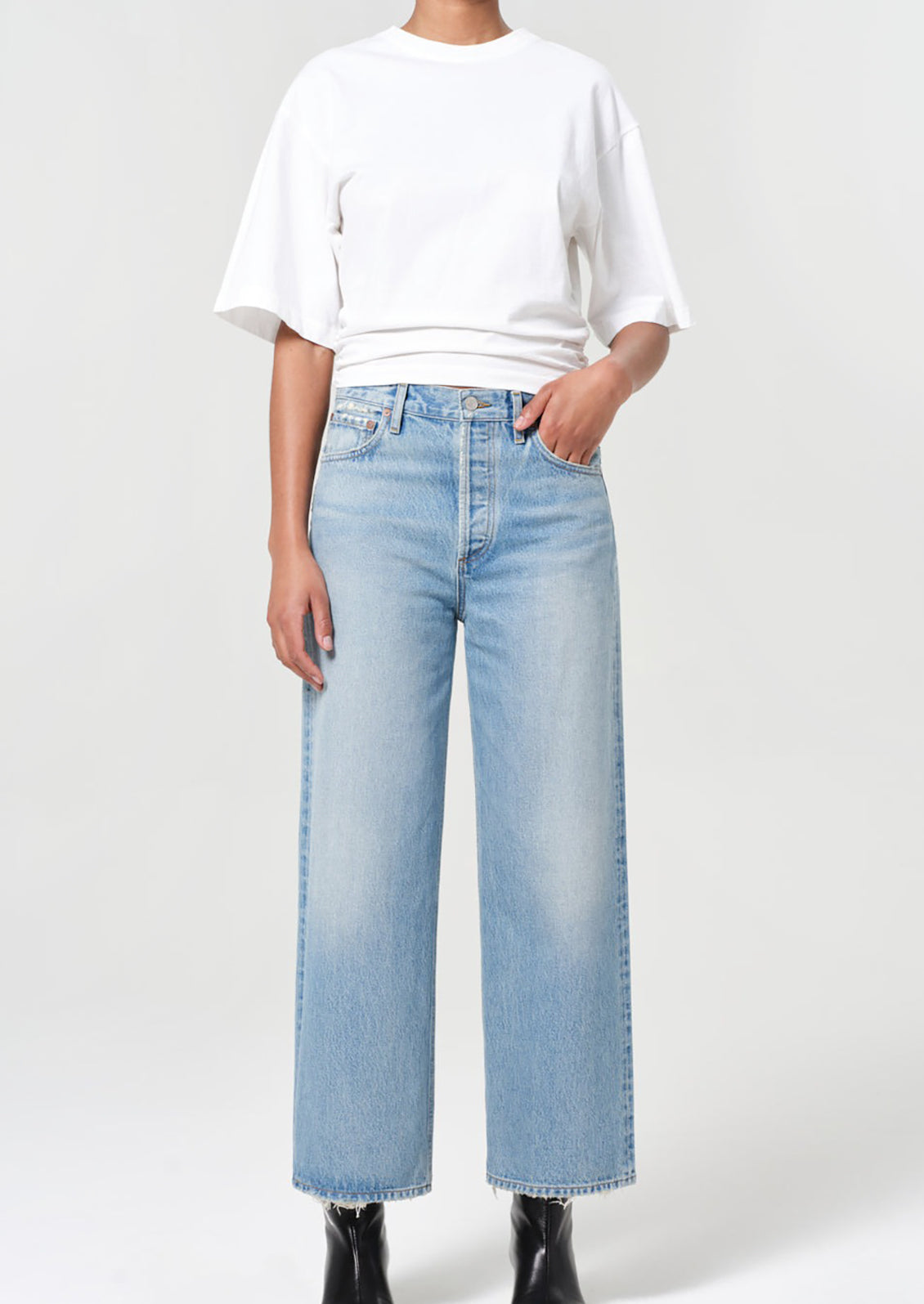 Person wearing a white t-shirt and light blue jeans on a plain background