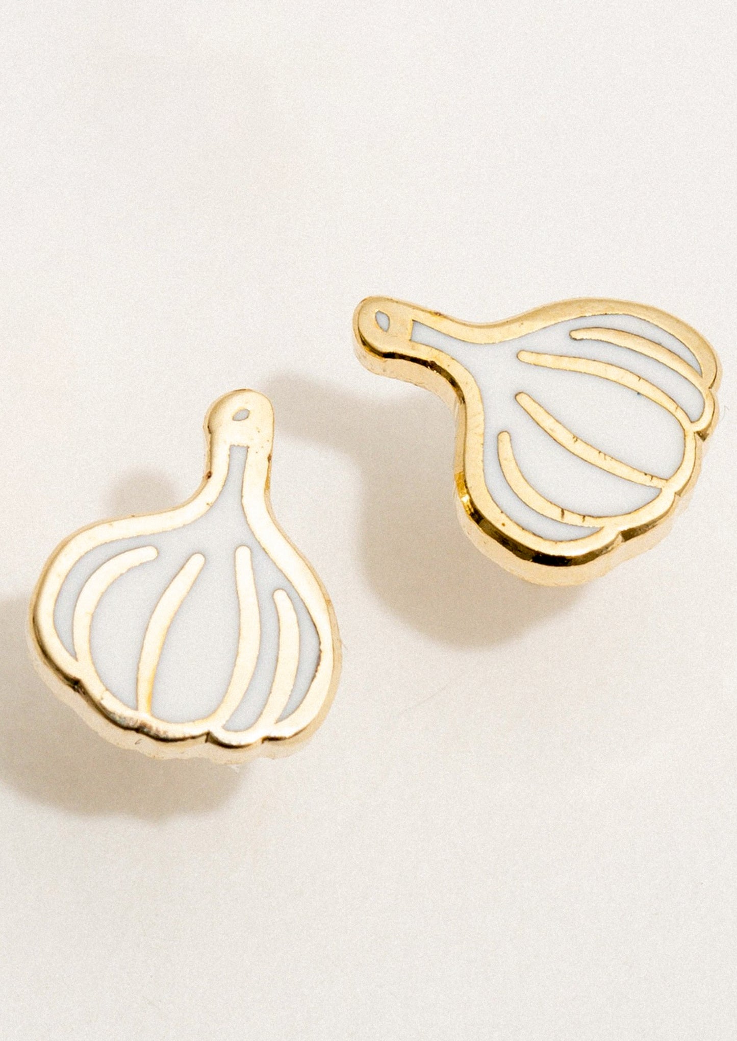 A pair of stud earrings in enamel depicting a bulb of garlic.