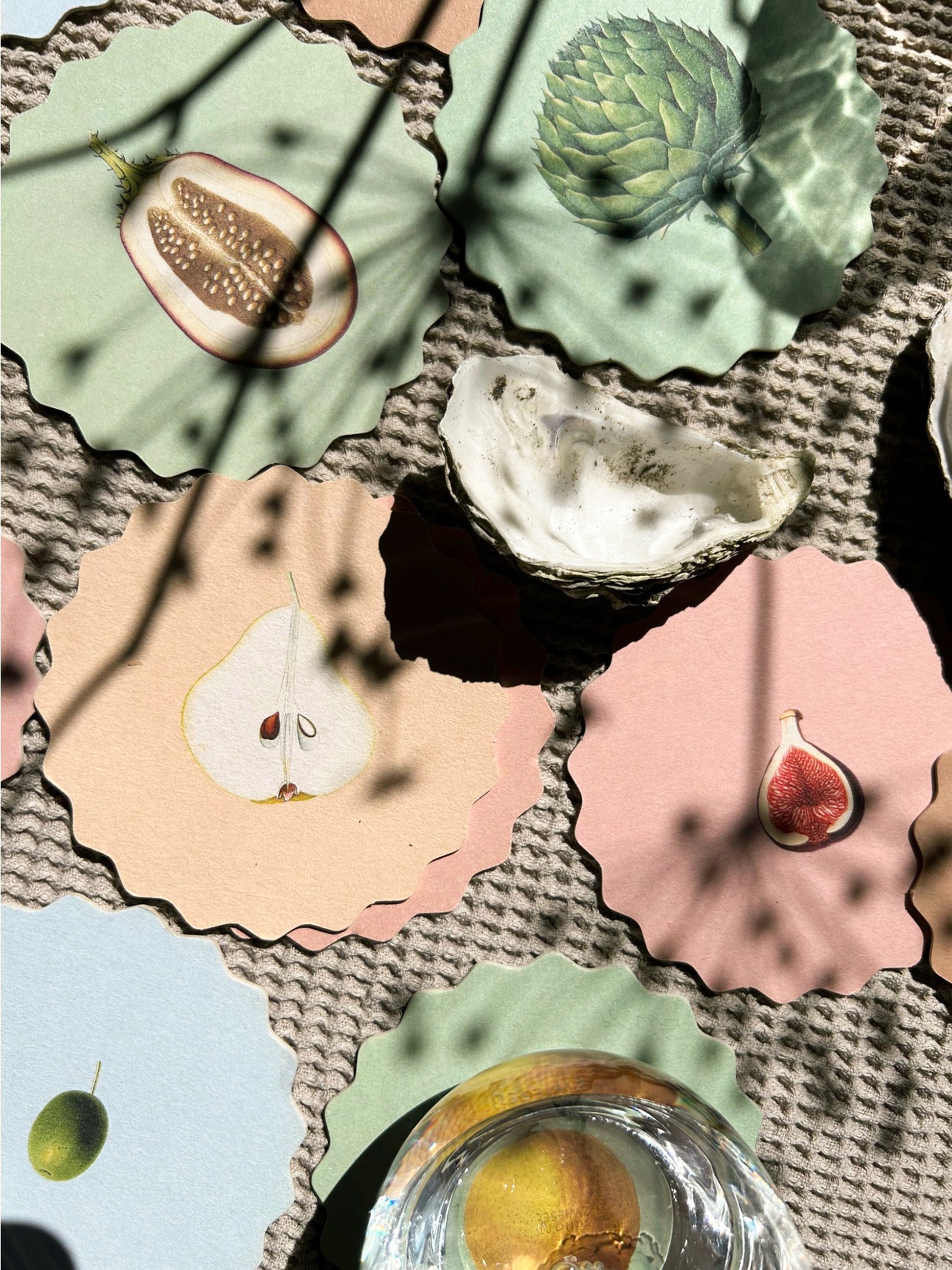 A set of scalloped edge paper coasters with 10 different fruit and vegetable prints.
