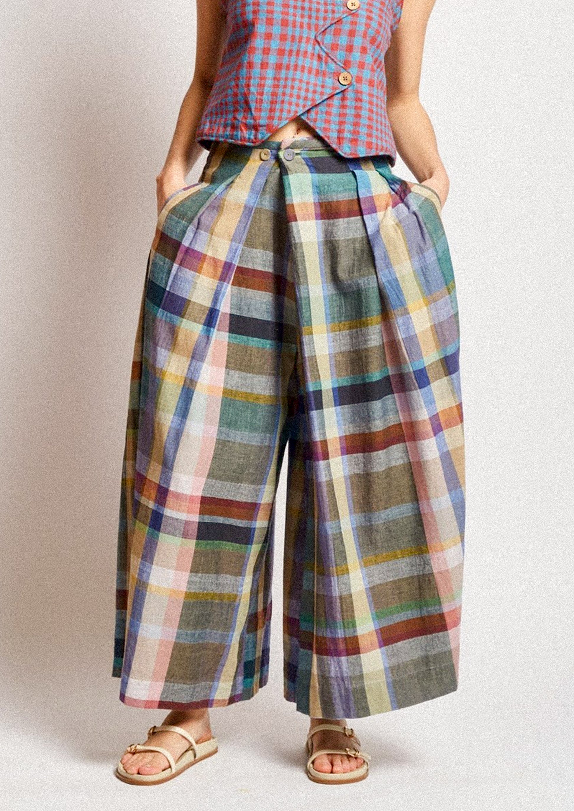 A woman wearing a pair of colorful multicolor check print wide leg pants.
