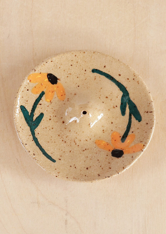 A speckled sand ceramic incense holder with hand painted sunflower design.