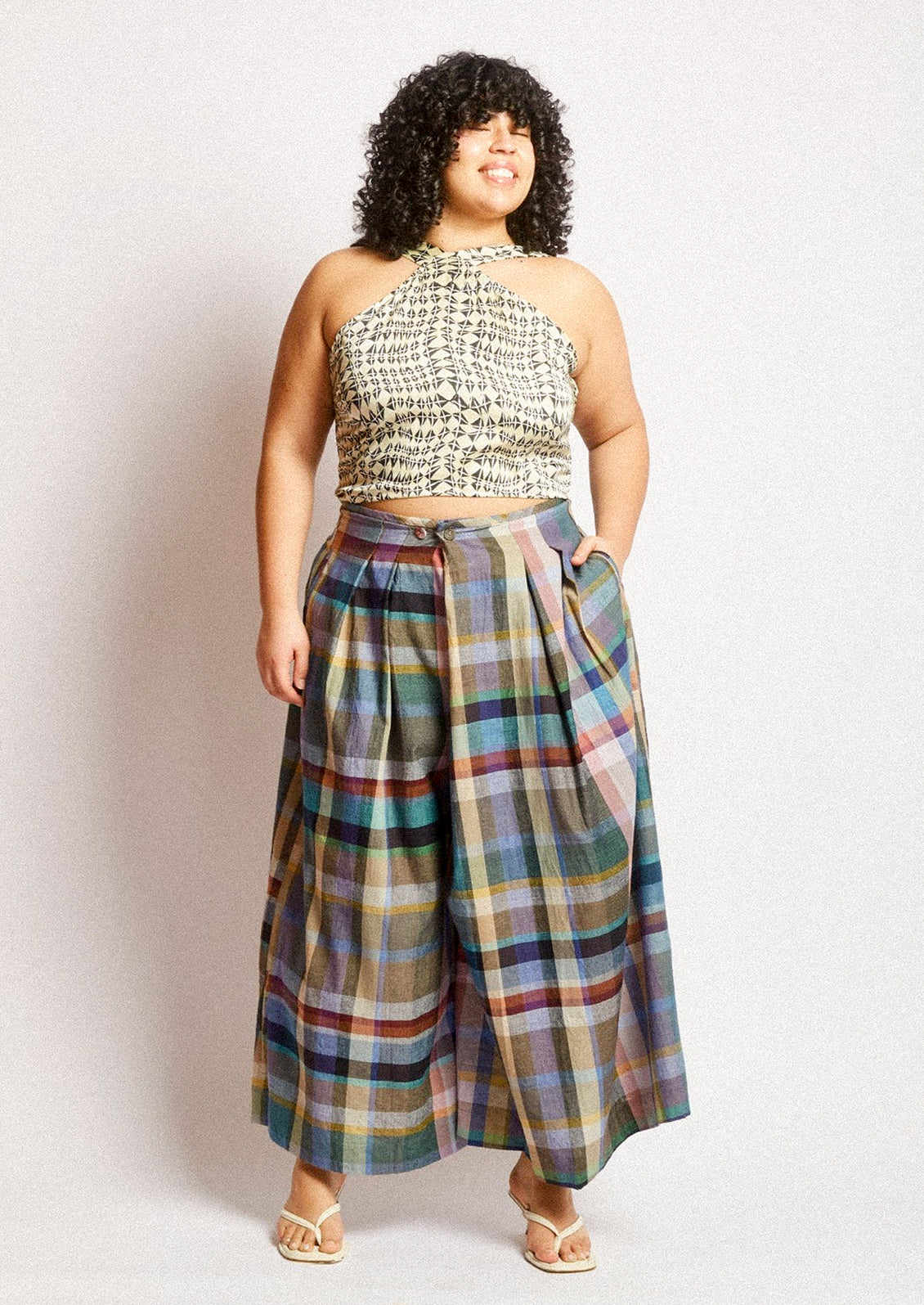 A woman wearing a pair of colorful multicolor check print wide leg pants.