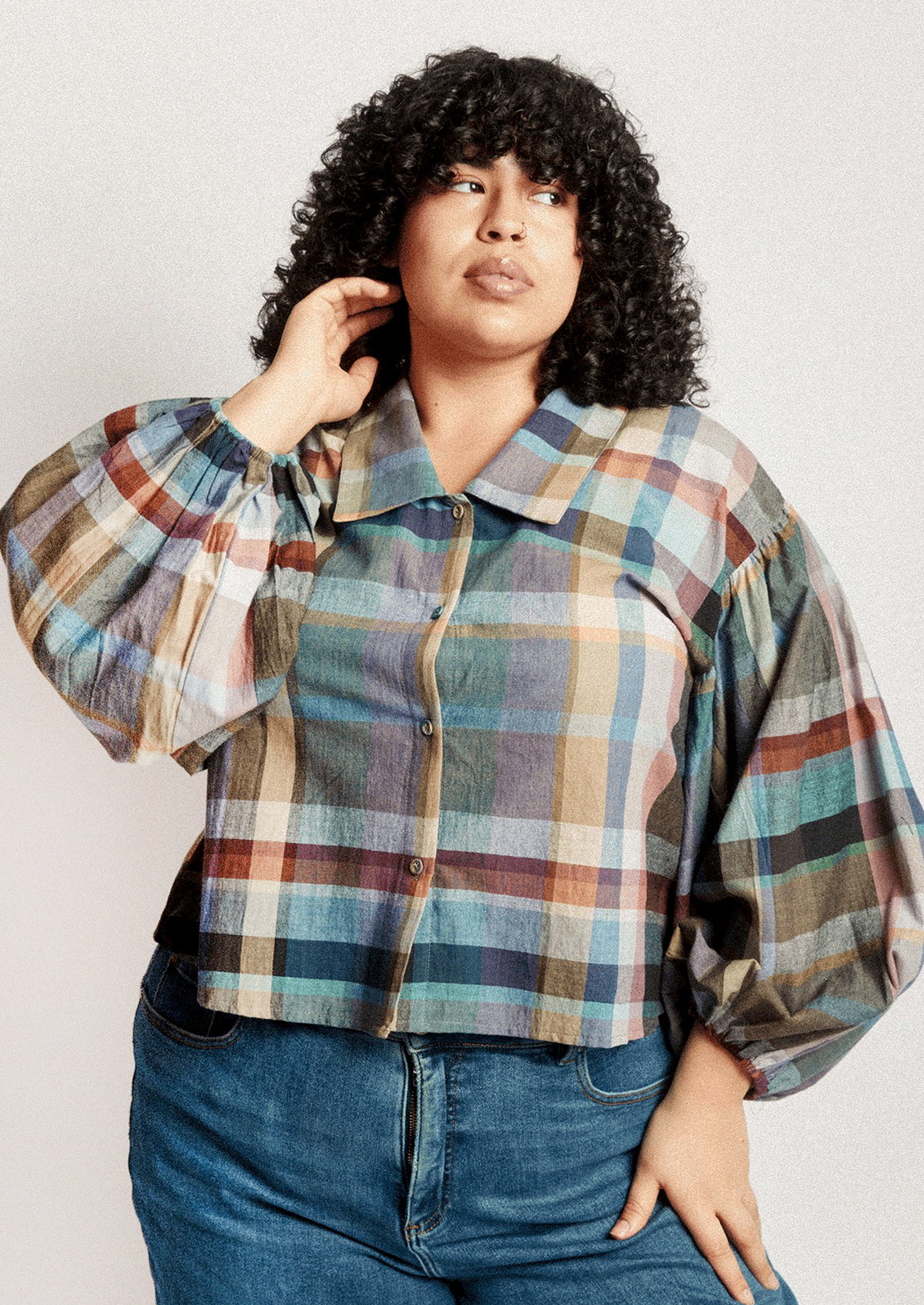 A person wearing a plaid print blouse with blouson sleeves.