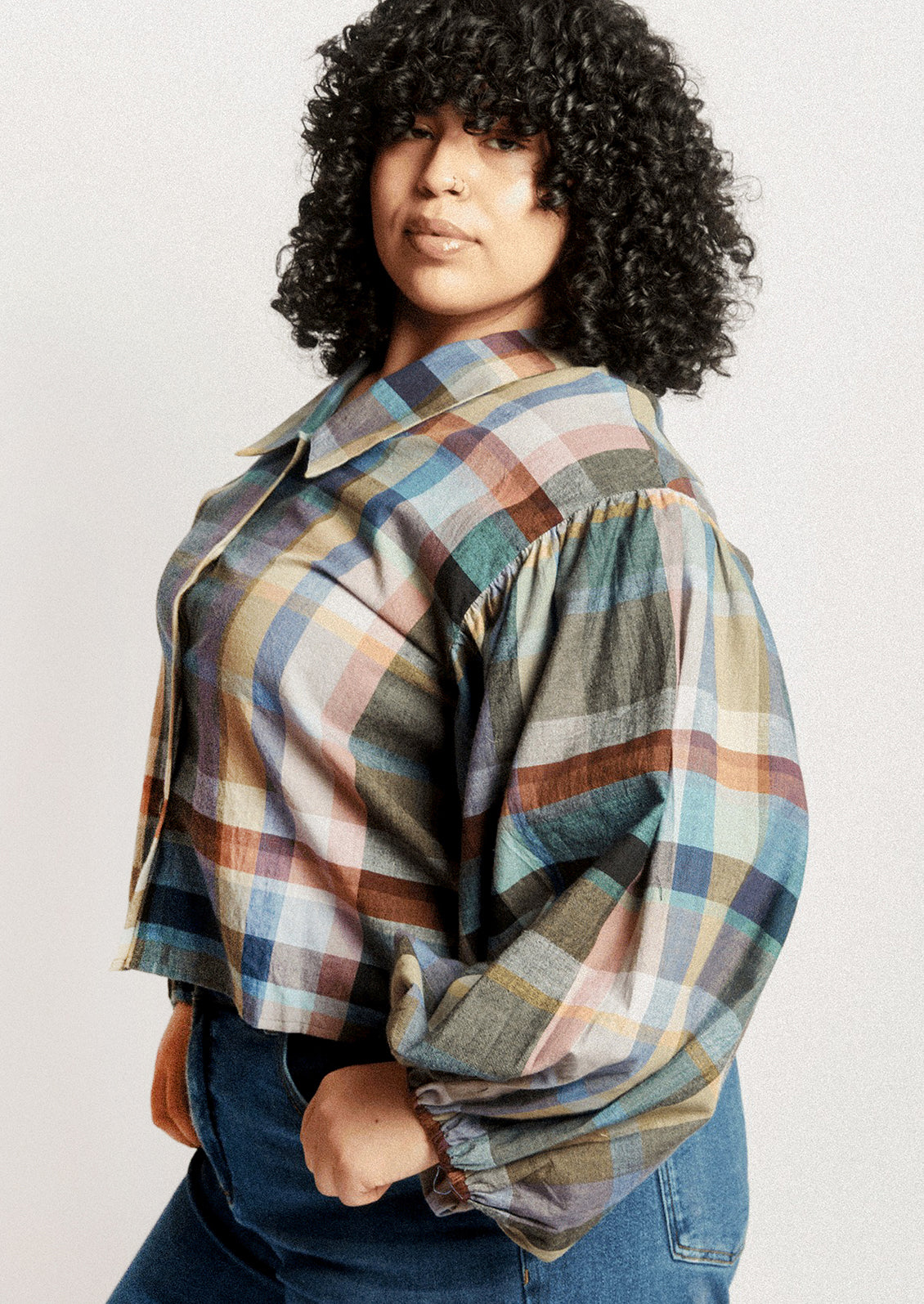 A person wearing a plaid print blouse with blouson sleeves.