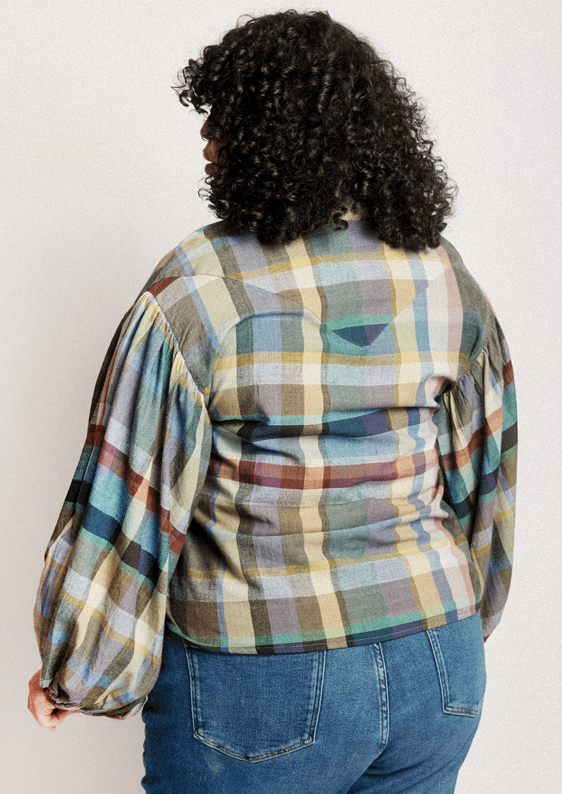 A person wearing a plaid print blouse with blouson sleeves.