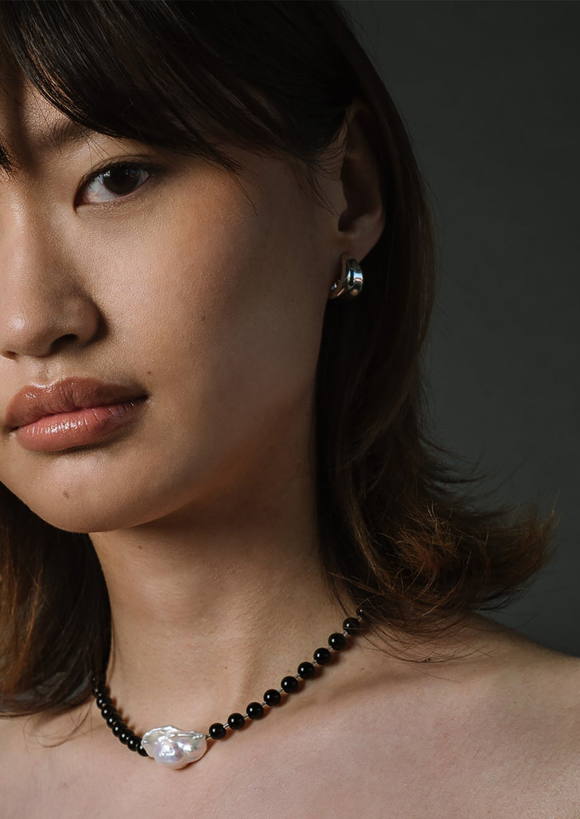 A pair of sterling silver hoop earrings with curled side detail.