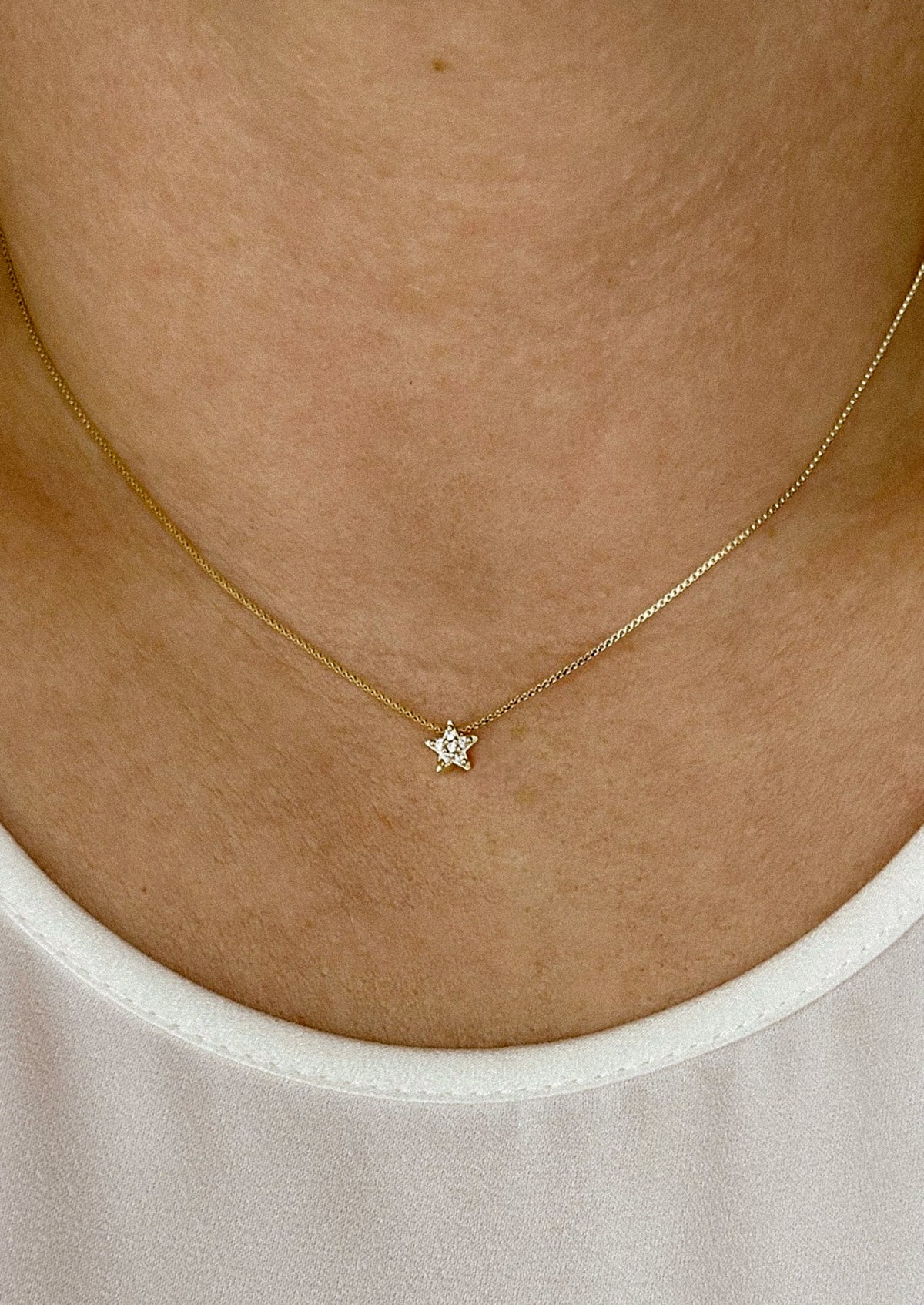 A gold box chain necklace with small gold & crystal star charm.