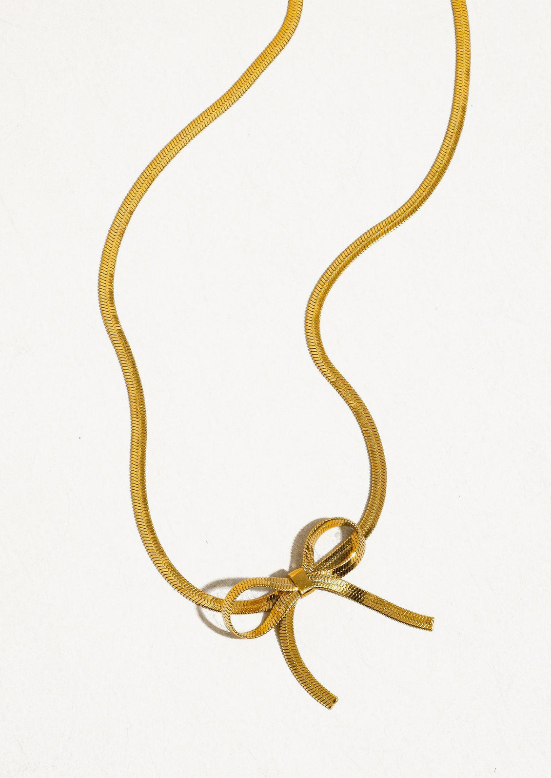 A gold choker-style necklace with bow shape at front.