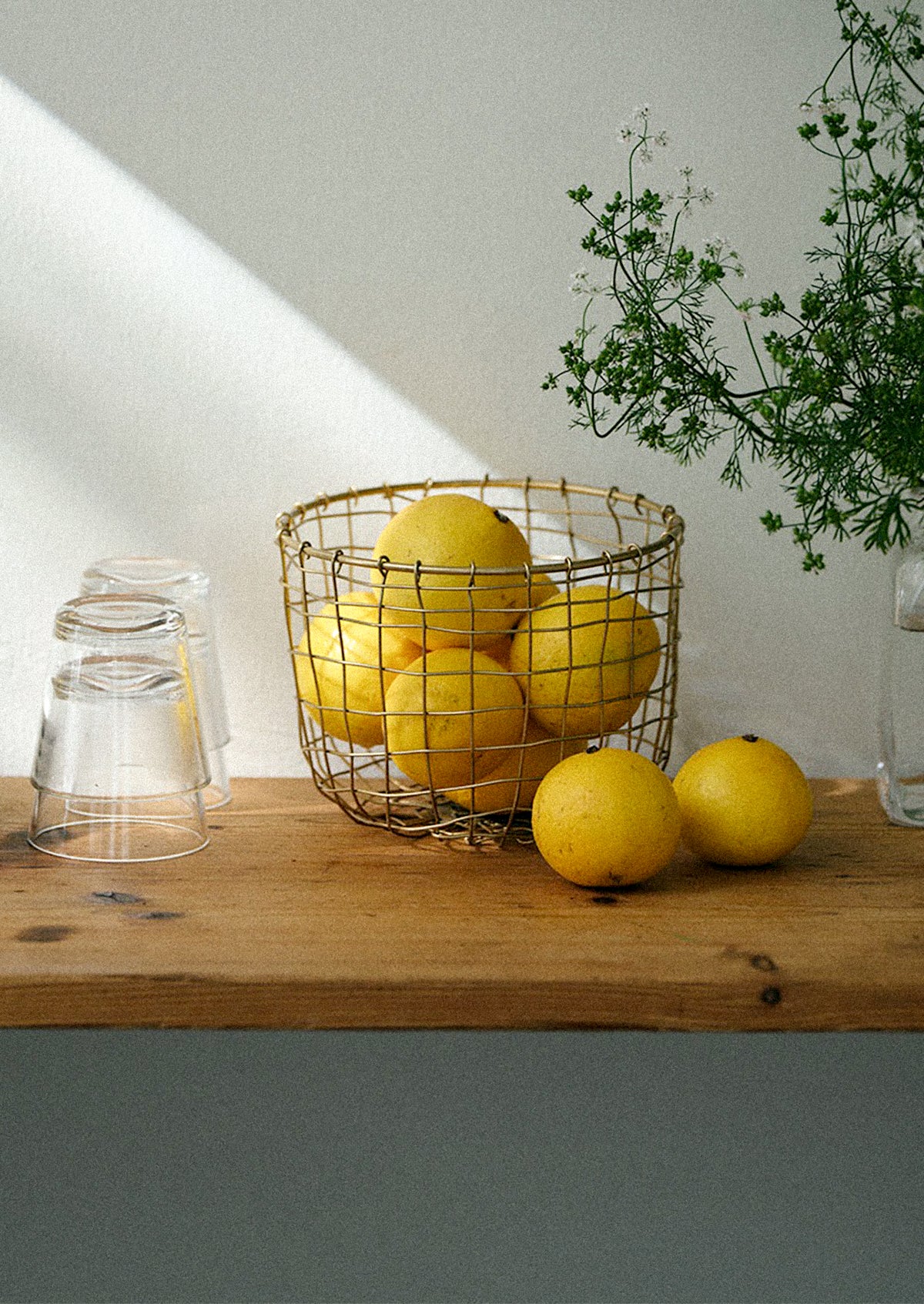 A round brass wire storage basket holding lemons.