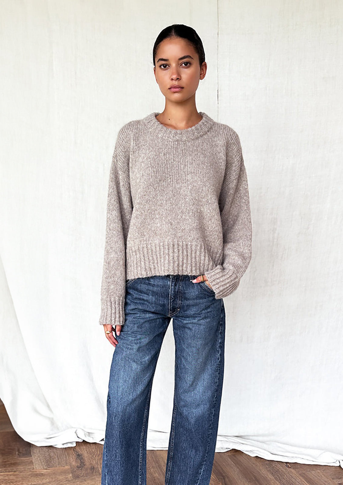 A woman wearing a round neck sweater with ribbed hem and cuffs.