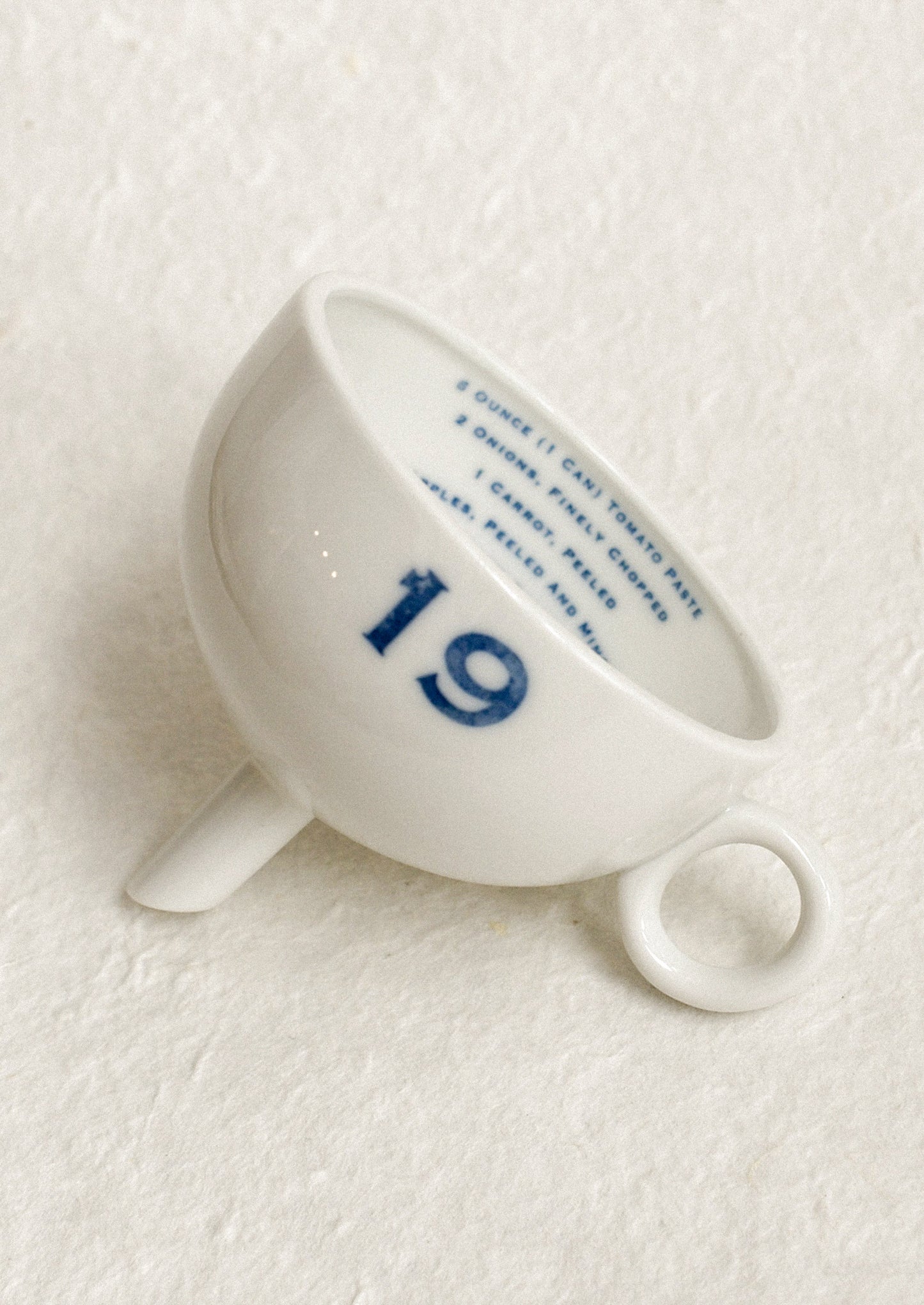 A ceramic funnel in white with printed blue text.