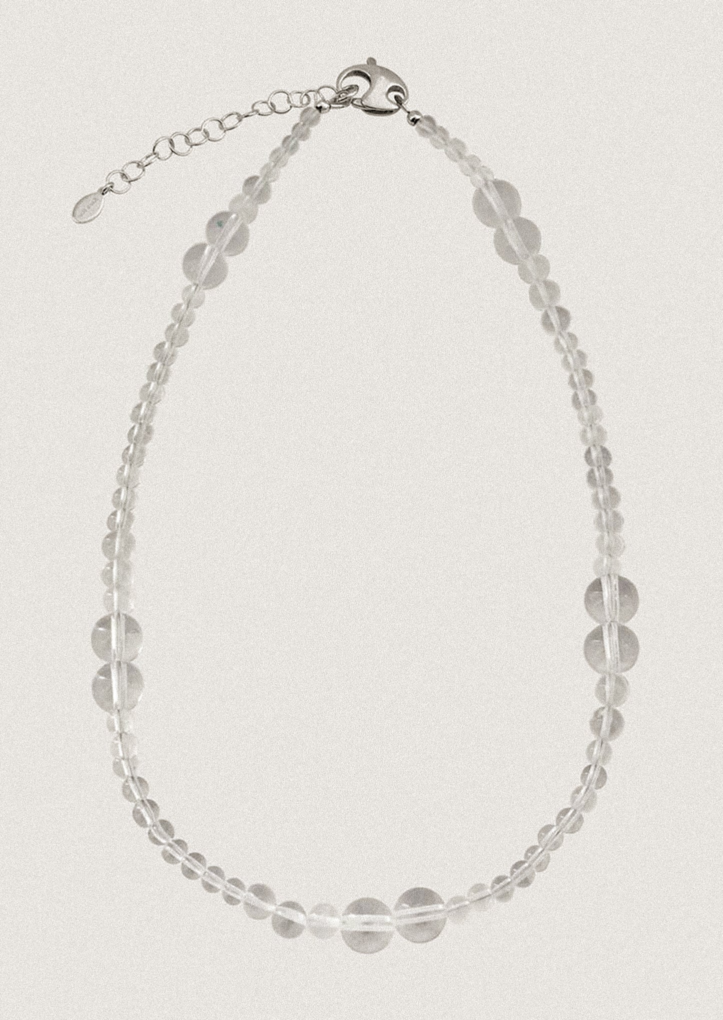 A beaded necklace made of round clear quartz beads in varying sizes.