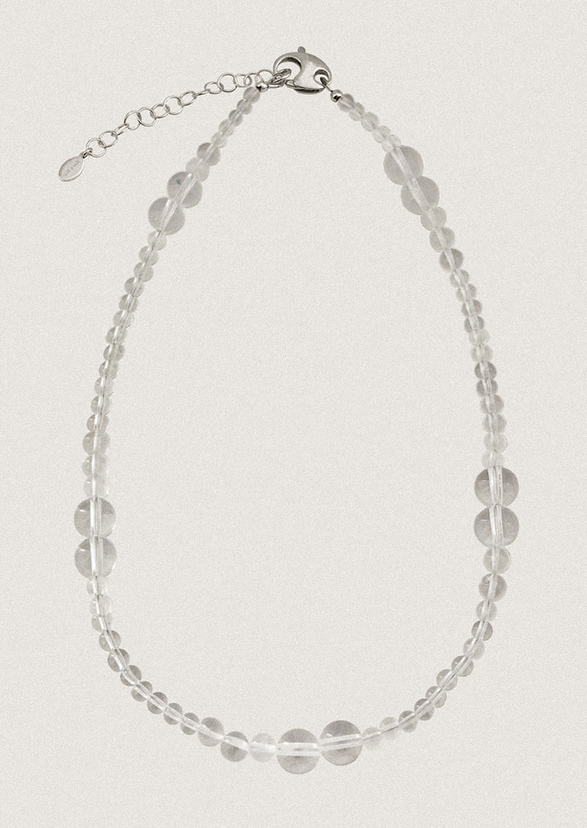 A beaded necklace made of round clear quartz beads in varying sizes.