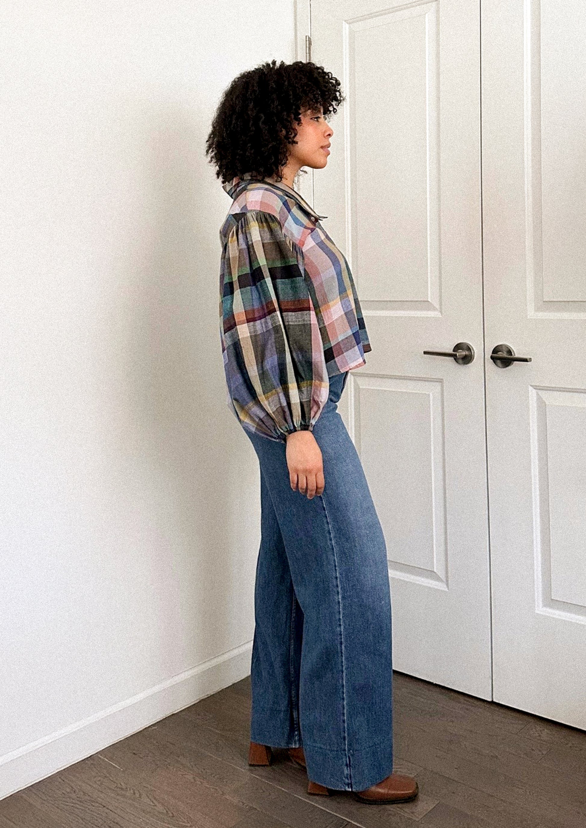 A person wearing a plaid print blouse with blouson sleeves.