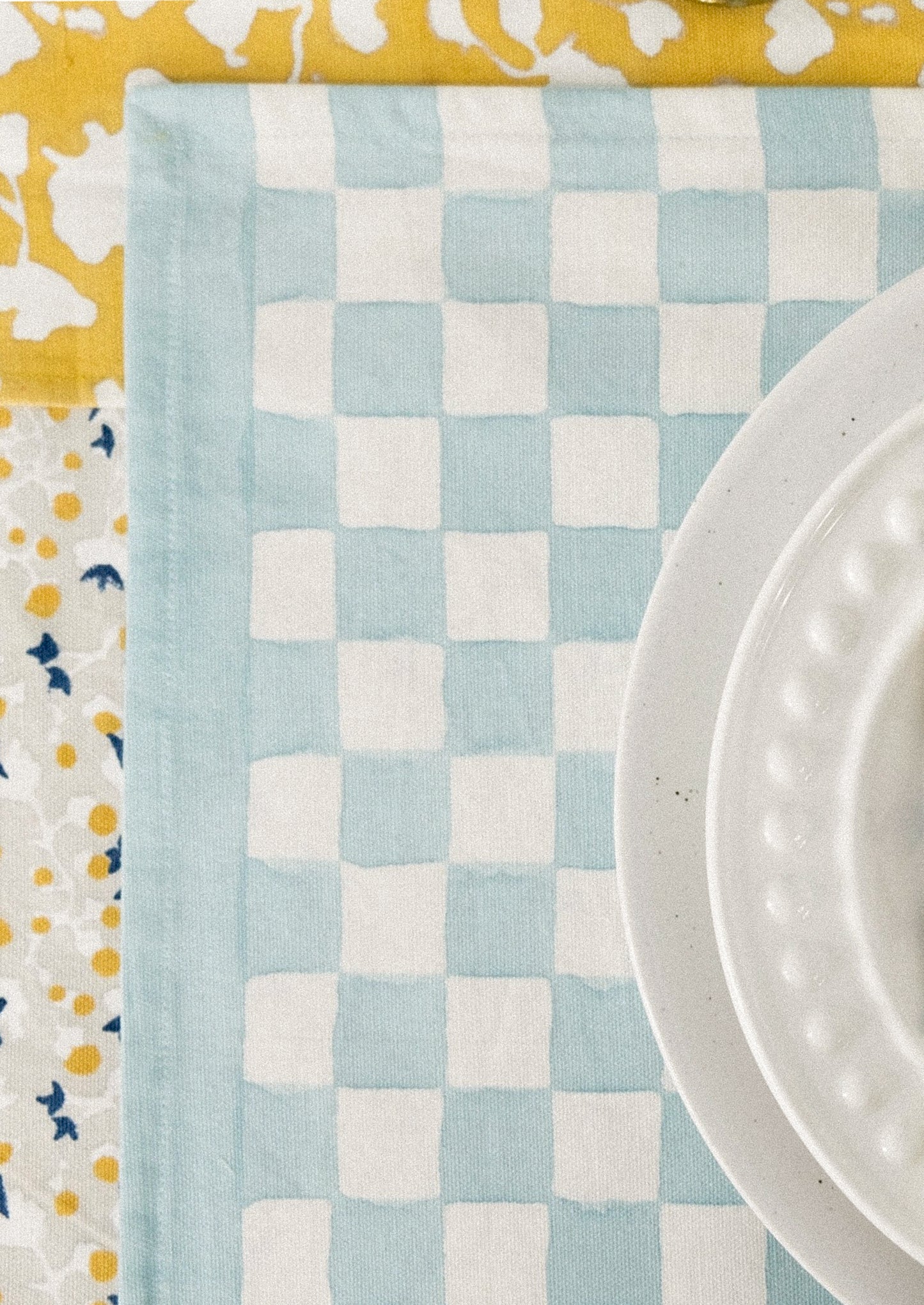 A block printed placemat with checkered pattern in sky blue.