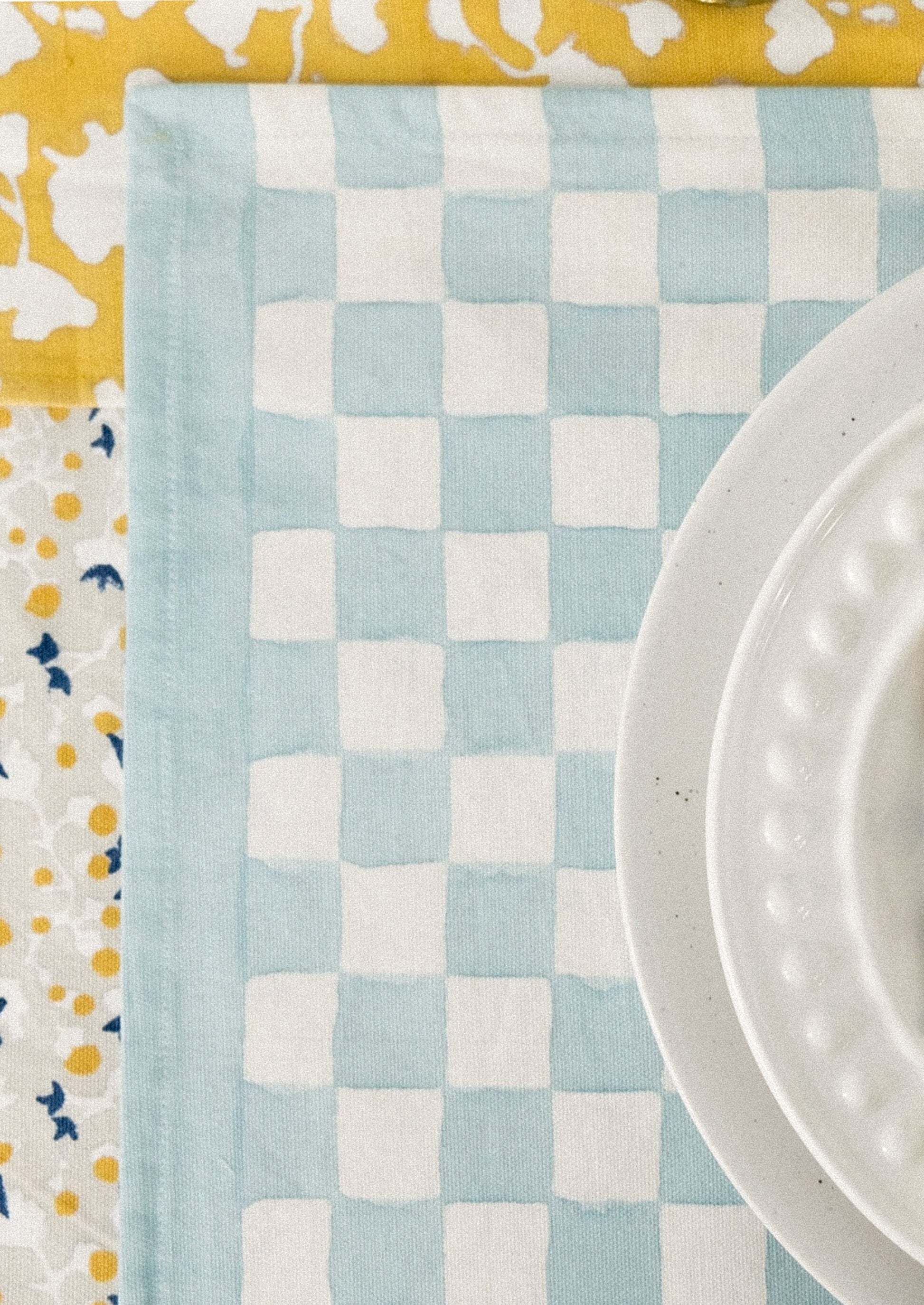 A block printed placemat with checkered pattern in sky blue.