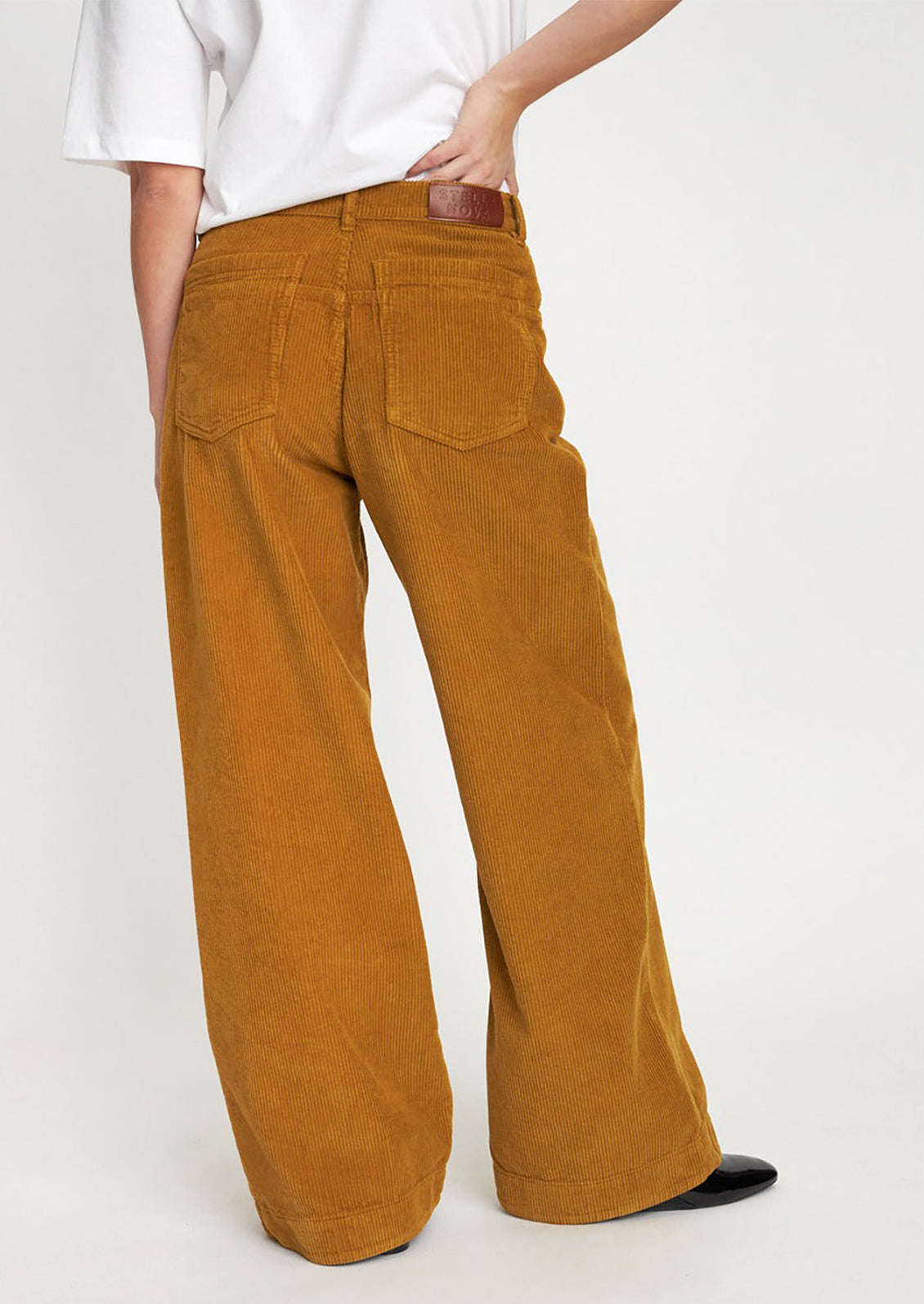 A woman wearing a pair of ochre colored wide leg corduroy pants.