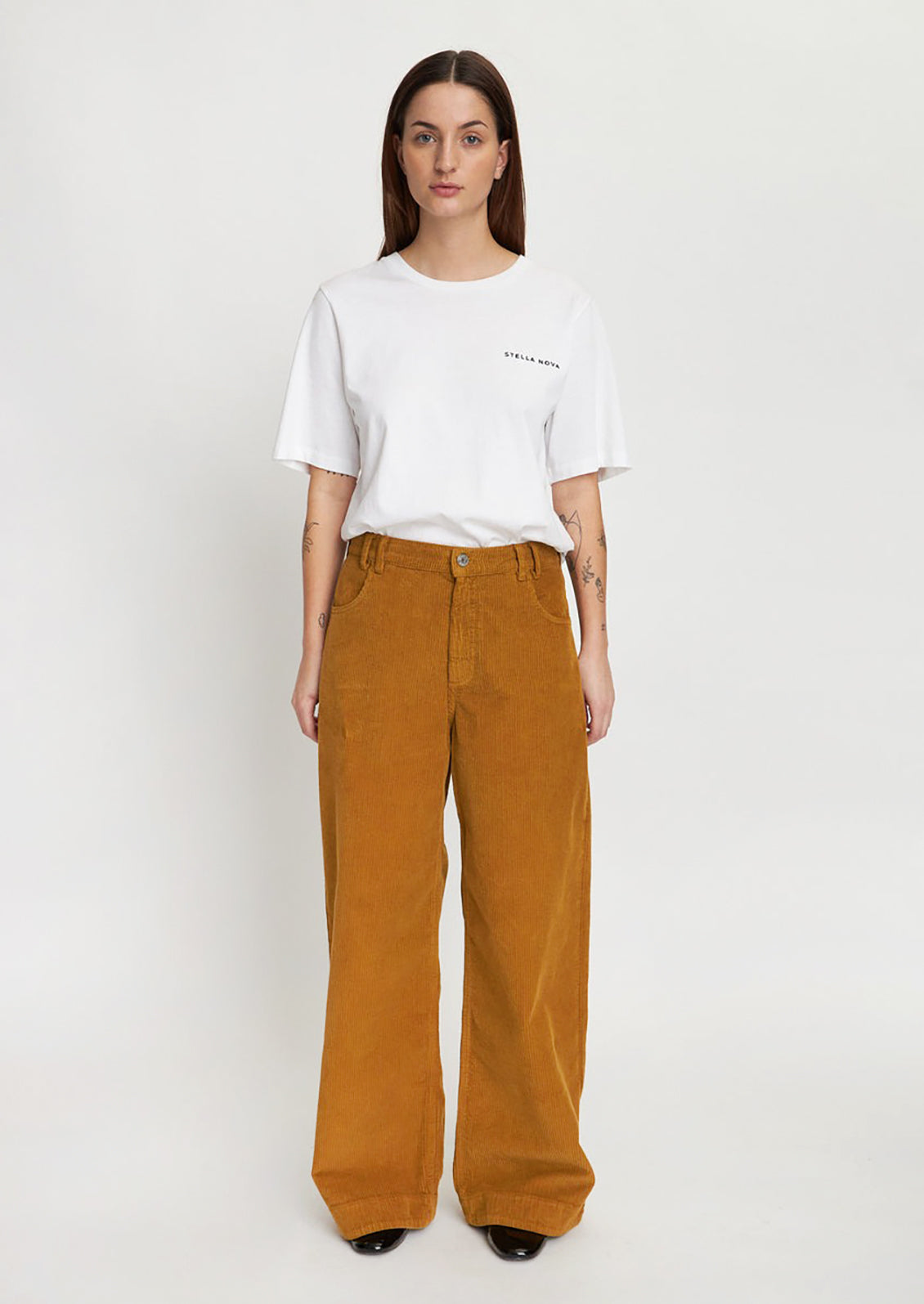 A woman wearing a pair of ochre colored wide leg corduroy pants.