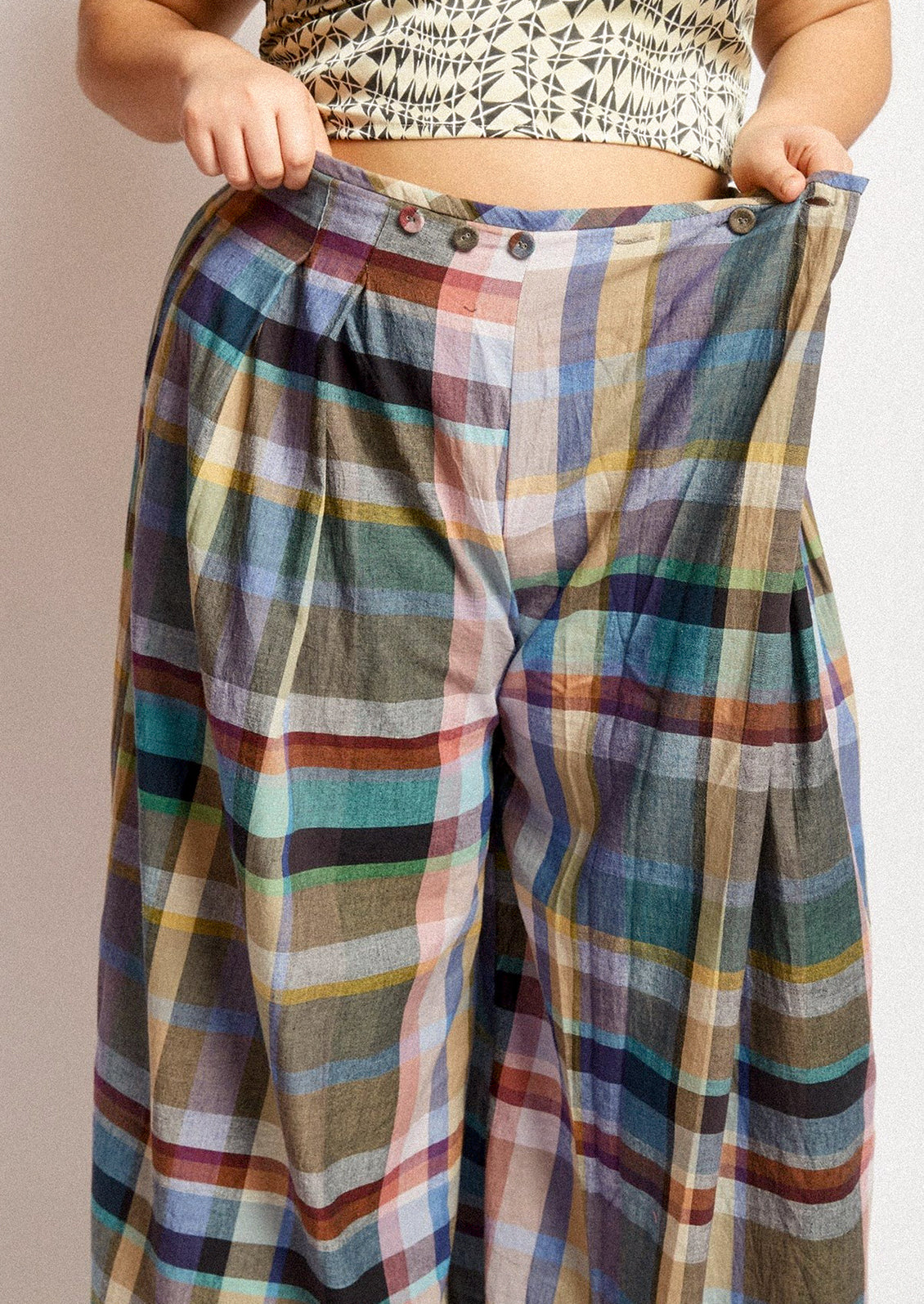 A woman wearing a pair of colorful multicolor check print wide leg pants.