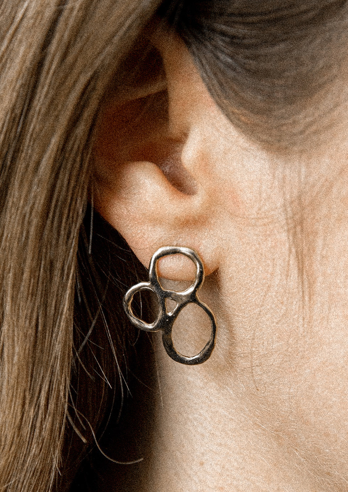 A pair of silver earrings with three organic circles melded together.