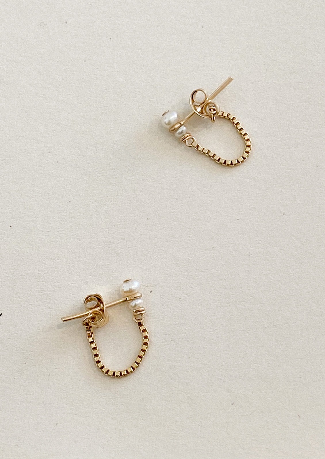 Gold  hoop earrings with pearl accents on a light gray background