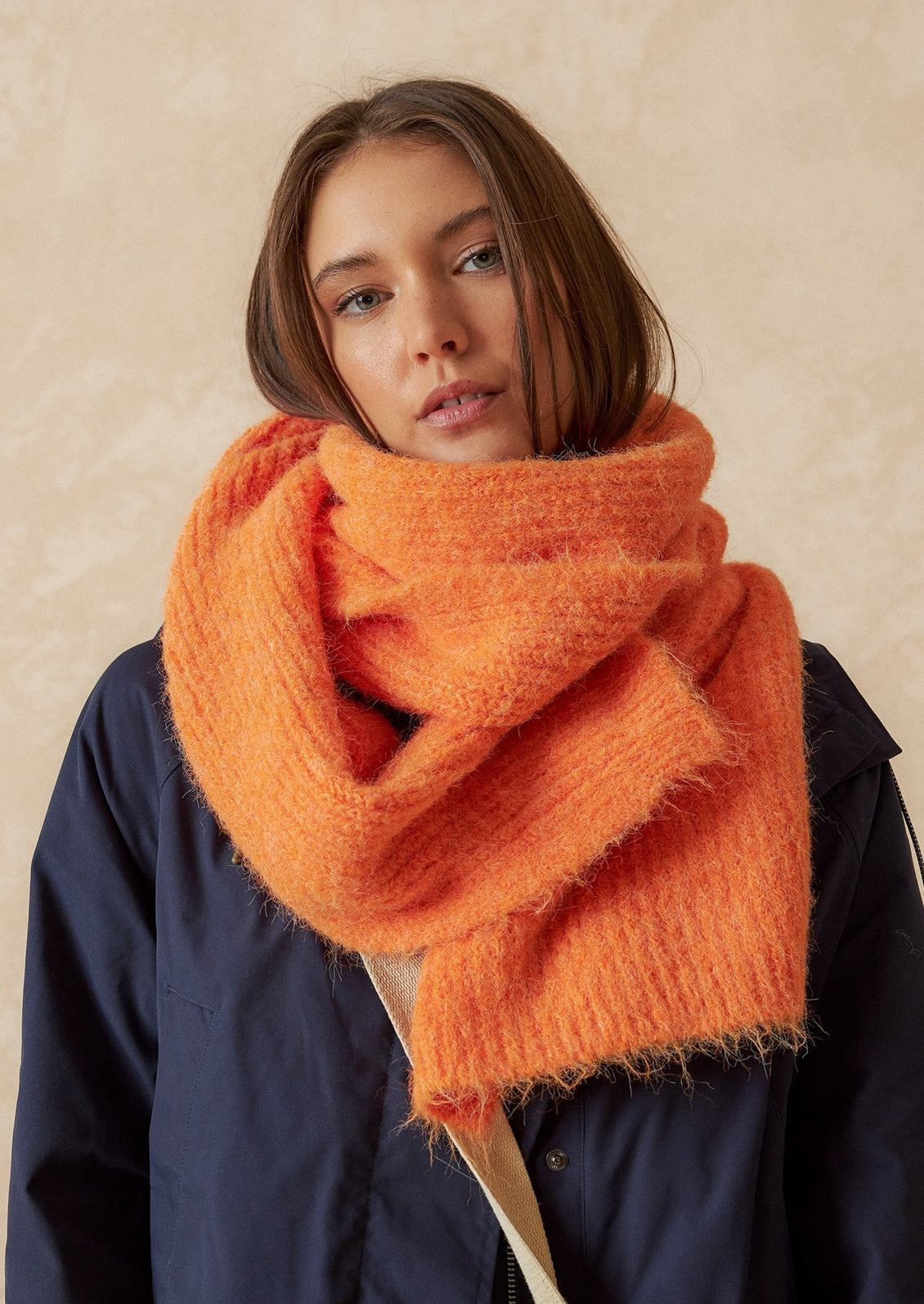 A woman wearing a fuzzy scarf in orange.