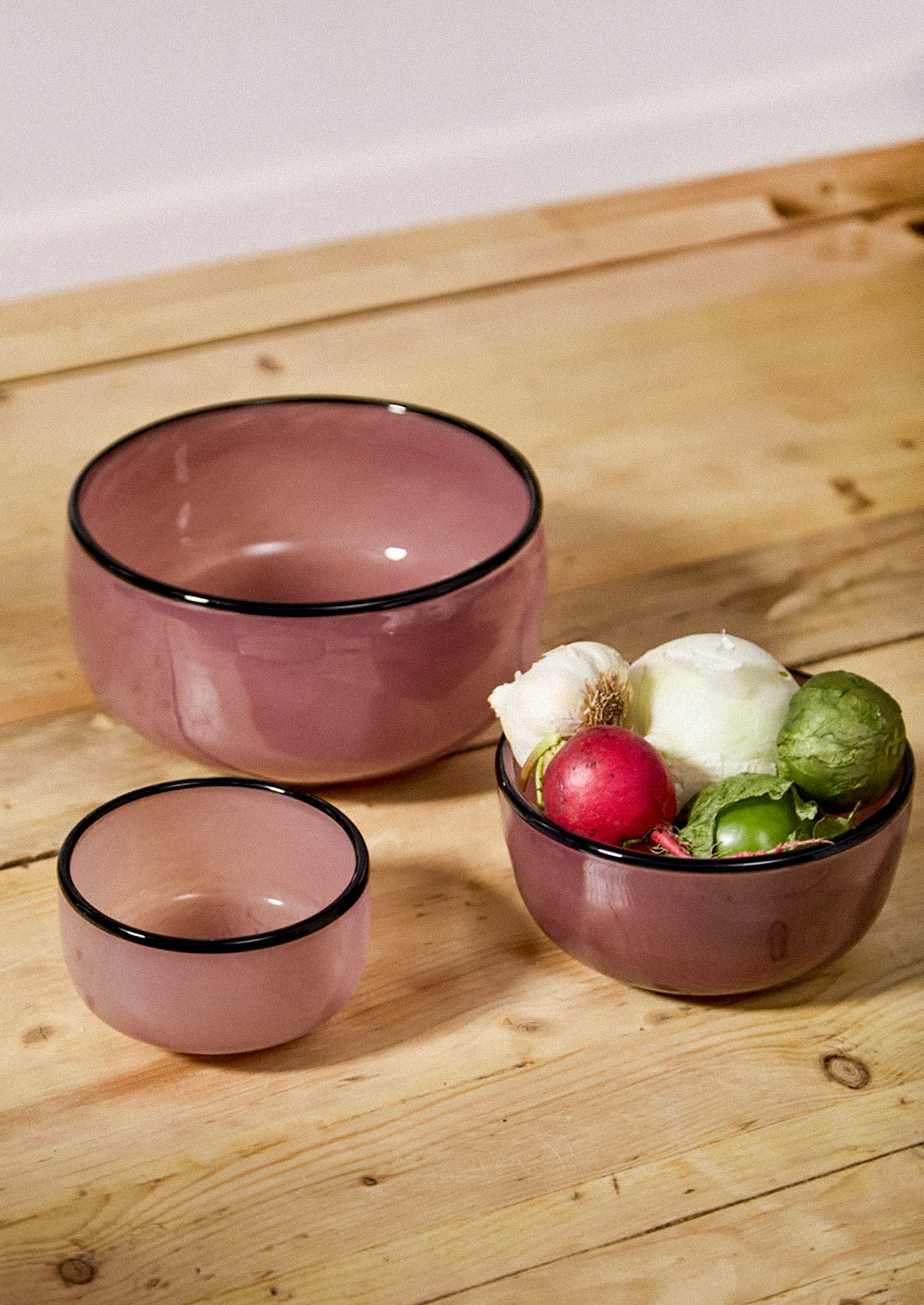 Glass bowls in mauve hue with black rim.