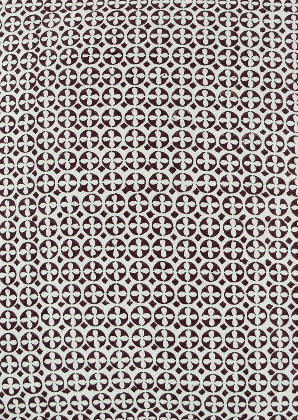 A lumbar throw pillow in white with geometric circular block print pattern in brown.