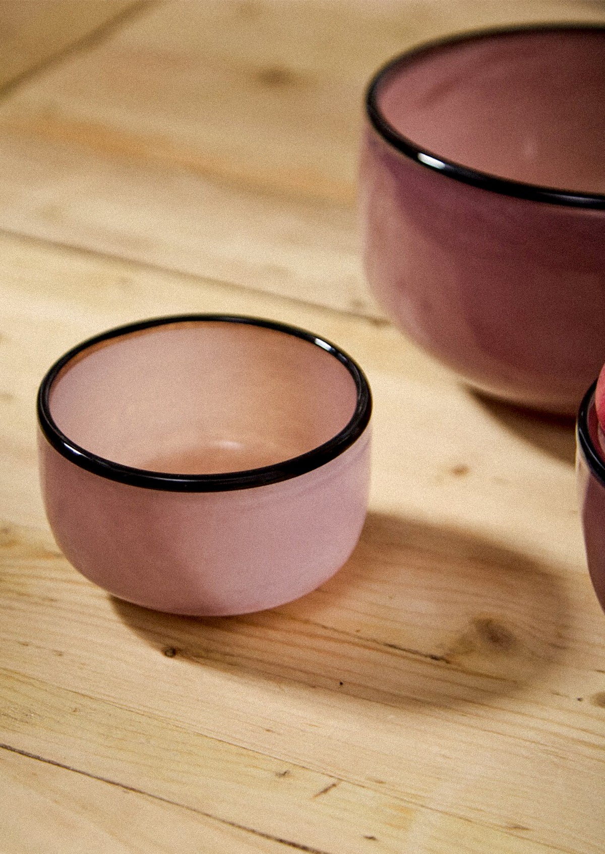 Glass bowls in mauve hue with black rim.