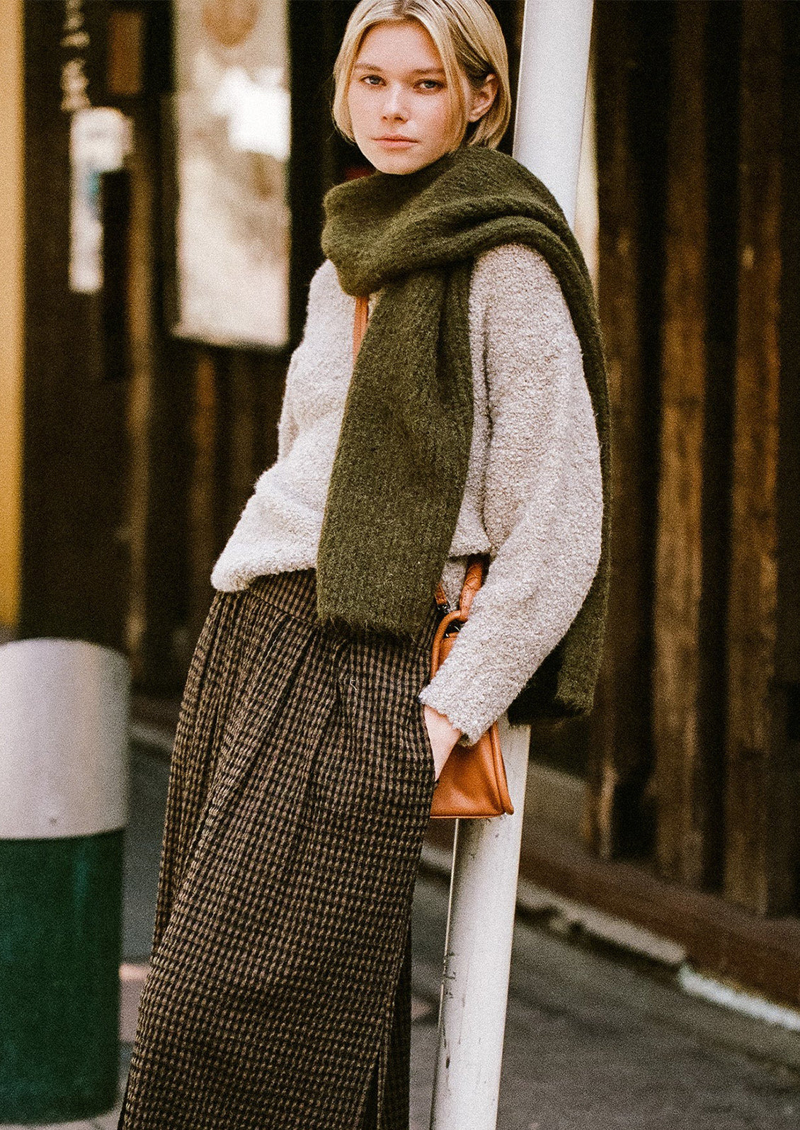 A woman wearing a fuzzy scarf in army green.